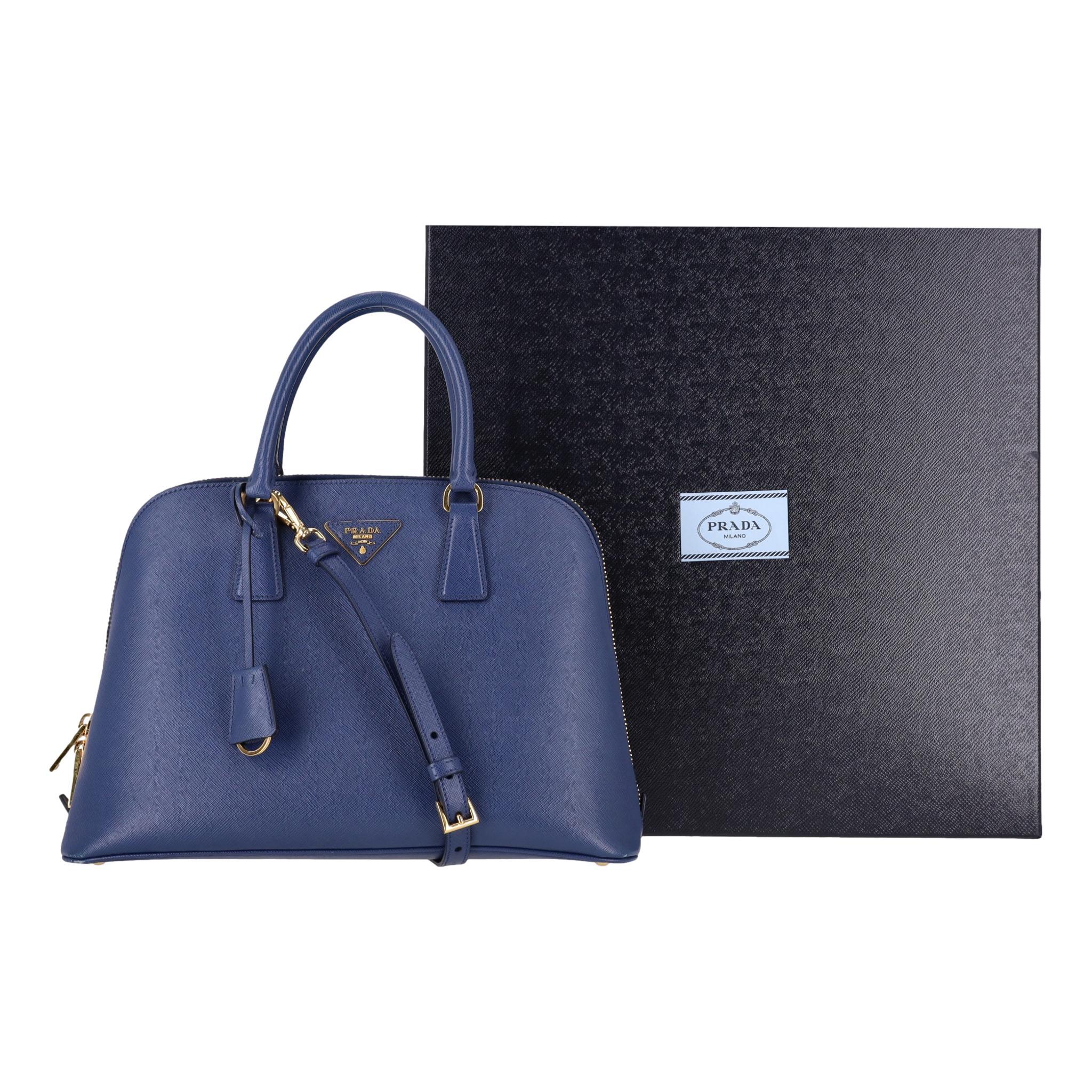 Prada Saffiano Leather Promenade Bag

Blue tote bag crafted of Prada signature Saffiano leather in blue.

'Prada' triangle logo to the front, rolled top handles with gold links and removable, adjustable shoulder strap.

Zipped top leading to