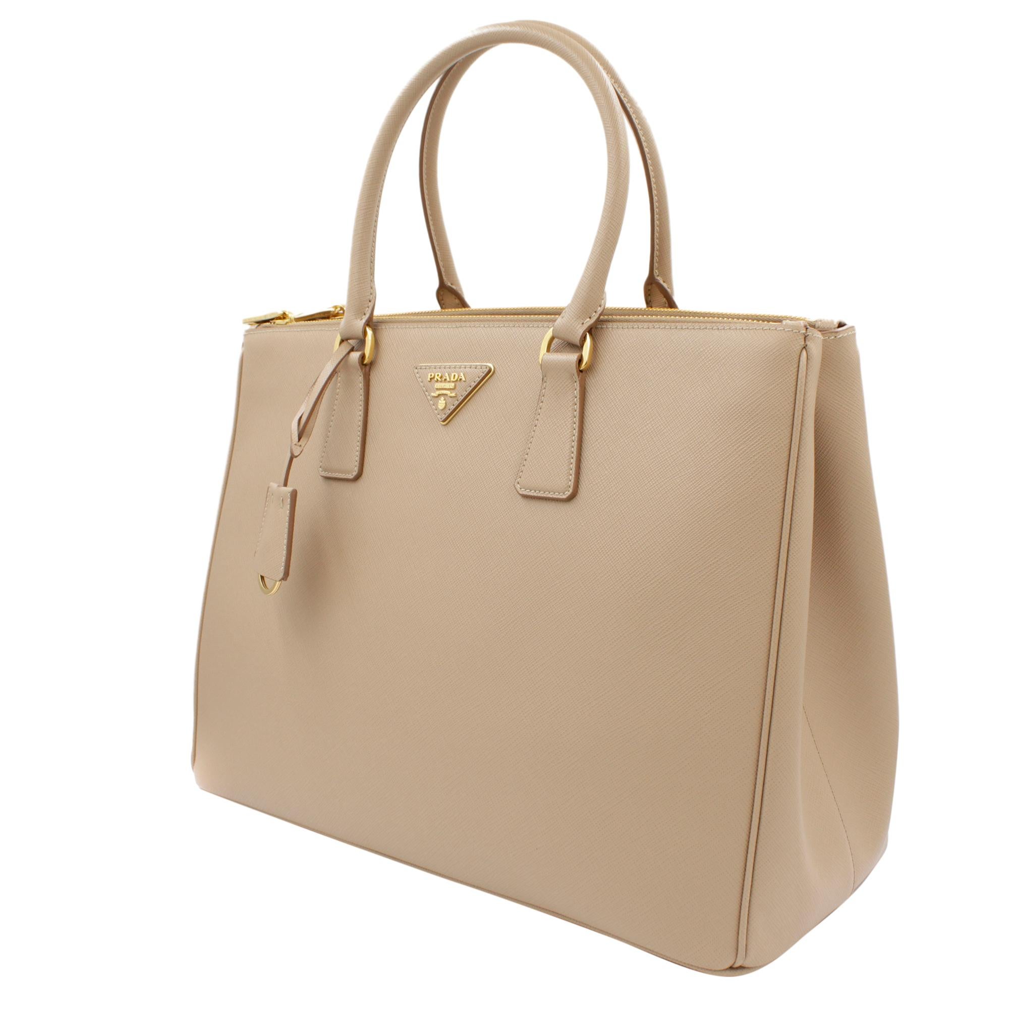 Prada's Galleria saffiano tote is a perfectly prim addition to your accessories edit. Crafted from textured beige calf leather, this design is finished with dainty top handles and golden hardware. Double storage compartments leave ample room for