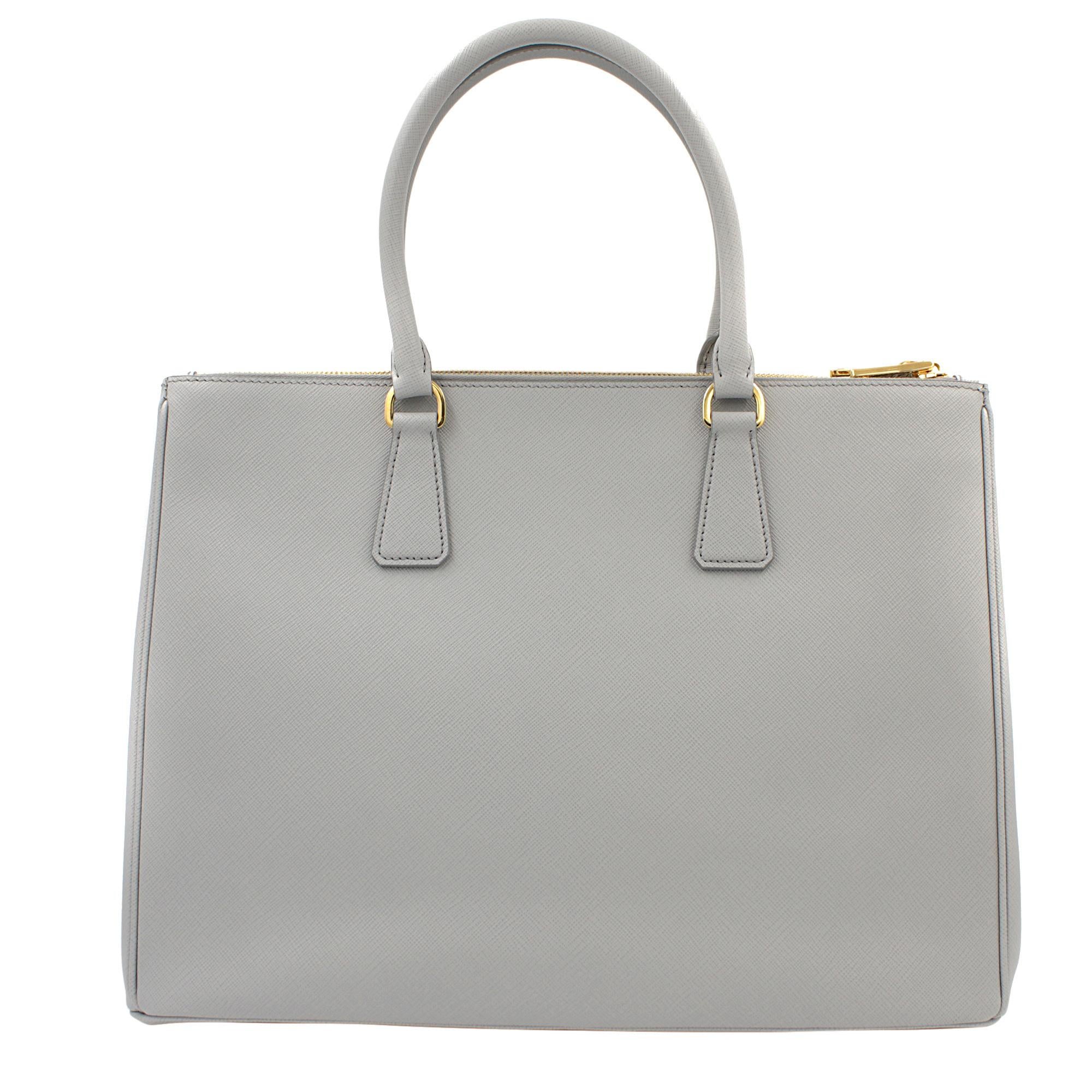 Prada's Galleria saffiano tote is a perfectly prim addition to your accessories edit. Crafted from textured gray calf leather, this design is finished with dainty top handles and golden hardware. Double storage compartments leave ample room for
