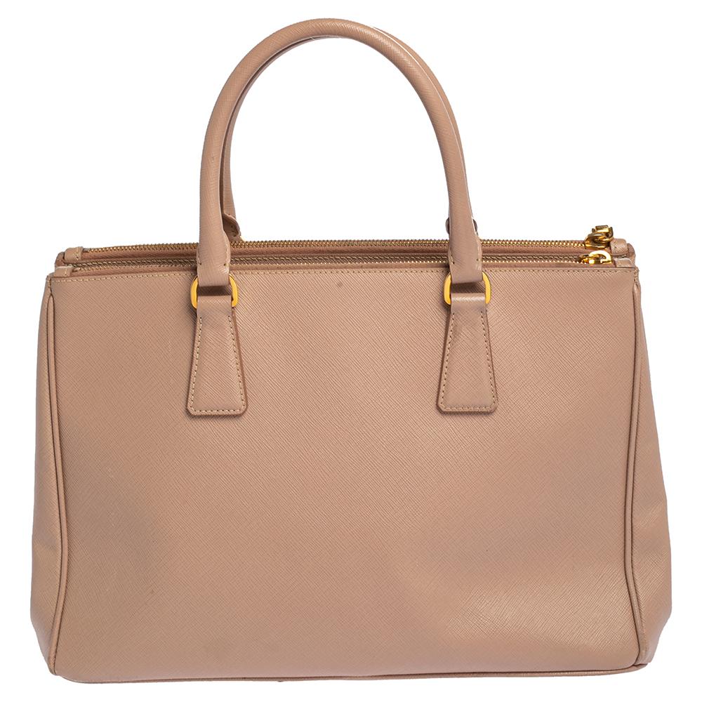 Loved for its classic appeal and functional design, Galleria is one of the most iconic and popular bags from the house of Prada. This beauty in dusty pink is crafted from Saffiano Lux leather and is equipped with two top handles, the brand logo at