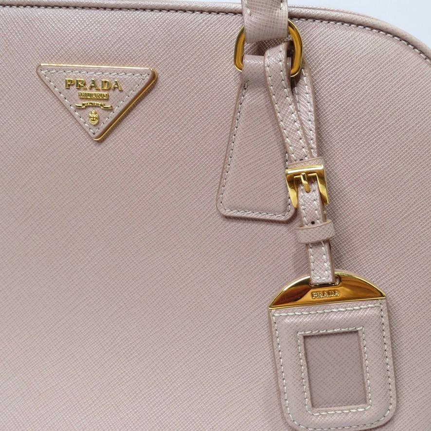 This Prada Saffiano Promenade handbag is the definition of understated elegance! Prada presents a neutral rendition of their iconic Promenade handbag in this versatile beige shade complimented by yellow gold hardware. The structure of this handbag