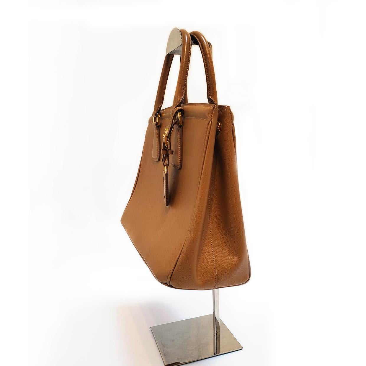 Brand - Prada
Collection - Saffiano Parabole
Estimated Retail - $2,350.00
Style - Tote
Material - Leather
Color - Caramel
Closure - Zip
Hardware Material - Goldtone
Comes With - Dustbag
Size - Large
Feature - Inner Dividers
Accent - Luggage