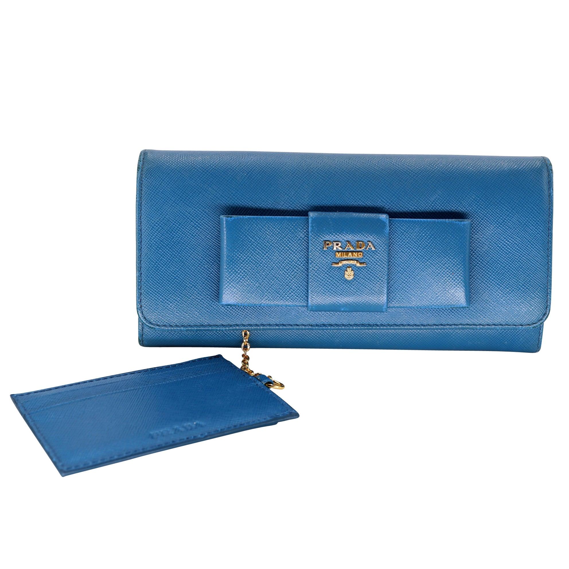 Dieses gebrauchte Prada Portemonnaie ist eine tolle Ergänzung für jede Handtasche oder Sammlung! Das Saffiano-Leder ist strapazierfähig und schön, und die goldfarbenen Beschläge verleihen ihm einen Hauch von Luxus. Der Knopfverschluss hält alles