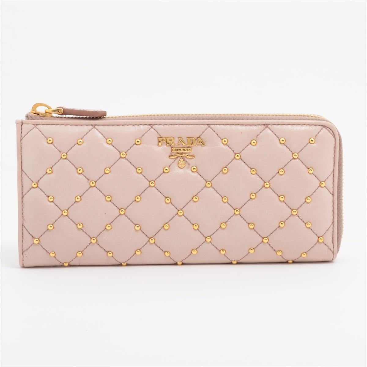 The Prada Saffiano Matelassé Studded Zippy Wallet in Beige is a luxurious and edgy accessory that combines elegance with a modern twist. Crafted from premium Saffiano leather, the wallet features a matelassé quilted design accented with sleek