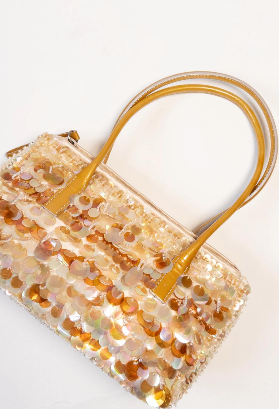 A dazzling nod to early 2000s charm, Prada’s mini pochette bag is reimagined in a cascade of light-catching sequins that shimmer with every movement. Rendered in a warm champagne hue with tonal beading, this compact silhouette captures the house’s