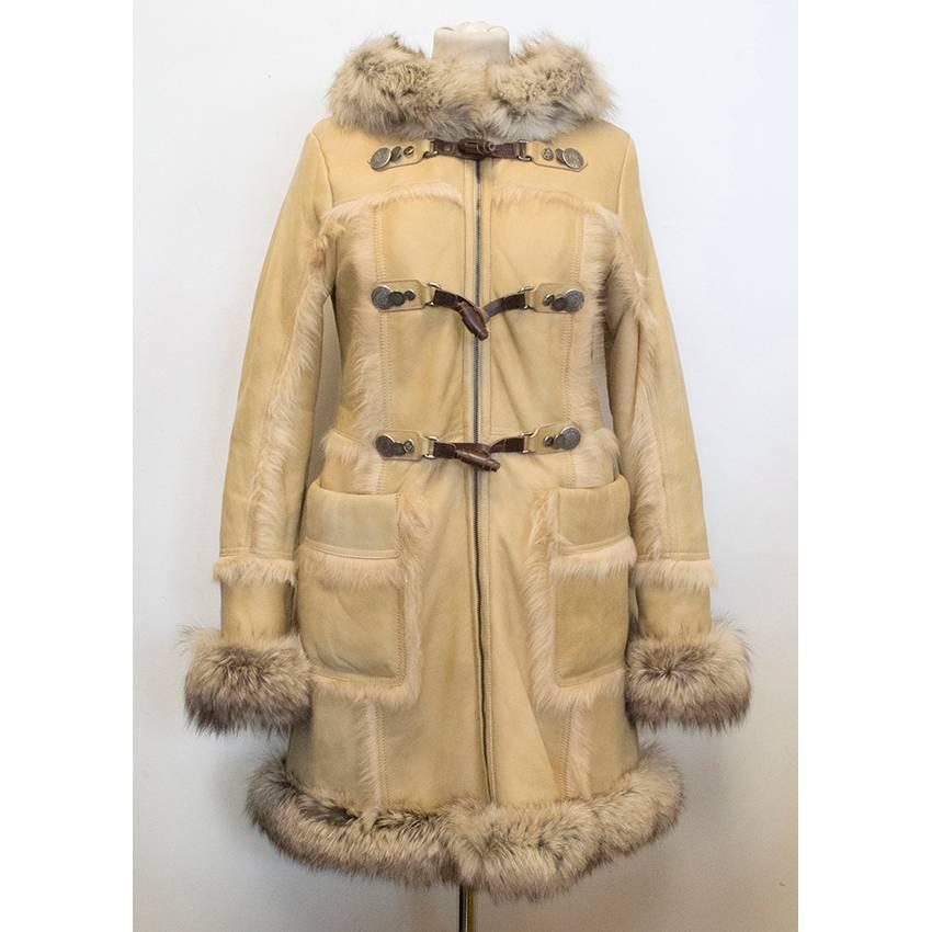 Beigefarbener Ledermantel mit Kapuze von Prada mit Kragen, Manschetten und Saum aus Fuchspelz und Schafspelzbesatz entlang der Nähte. Zwei große Funktionstaschen, Reißverschluss vorne und drei Knebelverschlüsse mit silberner Hardware. Der Mantel ist