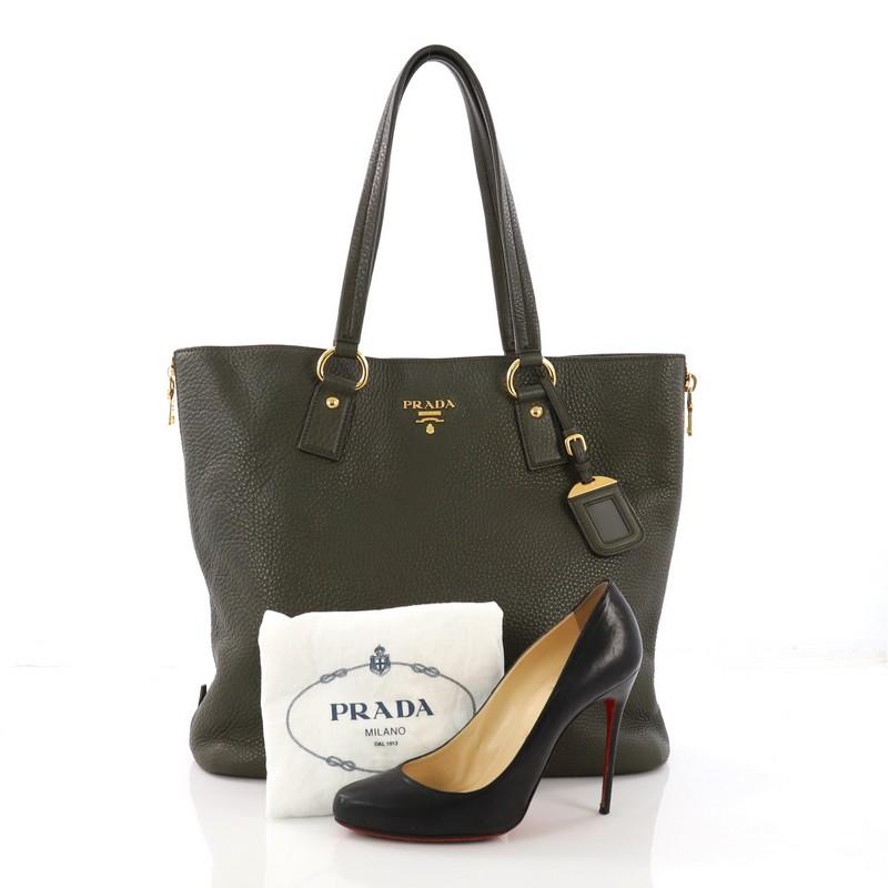 This Prada Side Zip Shopper Tote Vitello Daino Large, crafted from green vitello daino leather, features dual tall flat leather handles, zippered side gussets, and gold-tone hardware. Its magnetic snap closure opens to a dark brown fabric interior