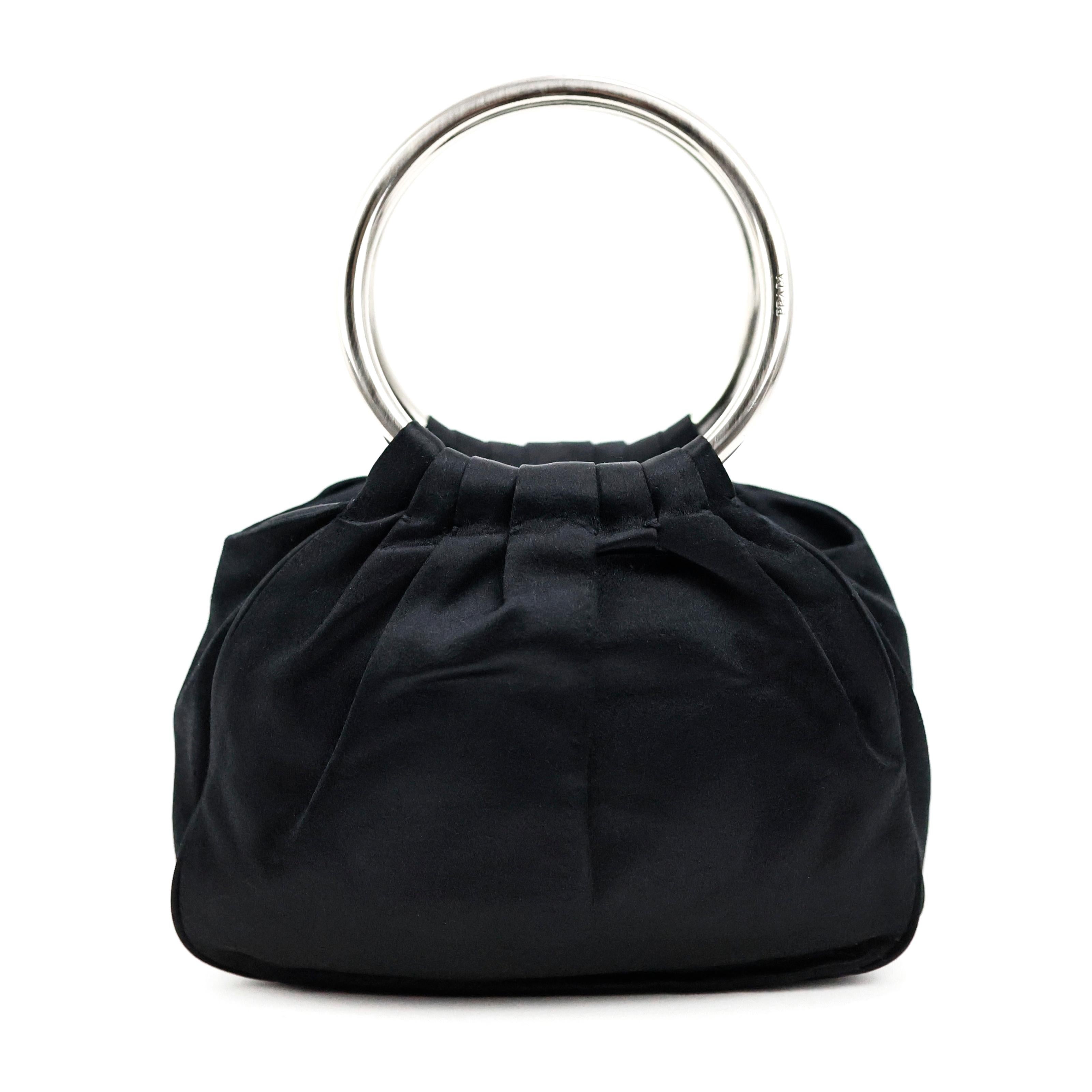 Prada ring handle bag in silk color black, silver hardware.

Condition:
Really good. To note: some pulled threads on silk.

Packing/accessories:
Dustbag, mirror.

Measurements:
18cm x 13cm x 8cm