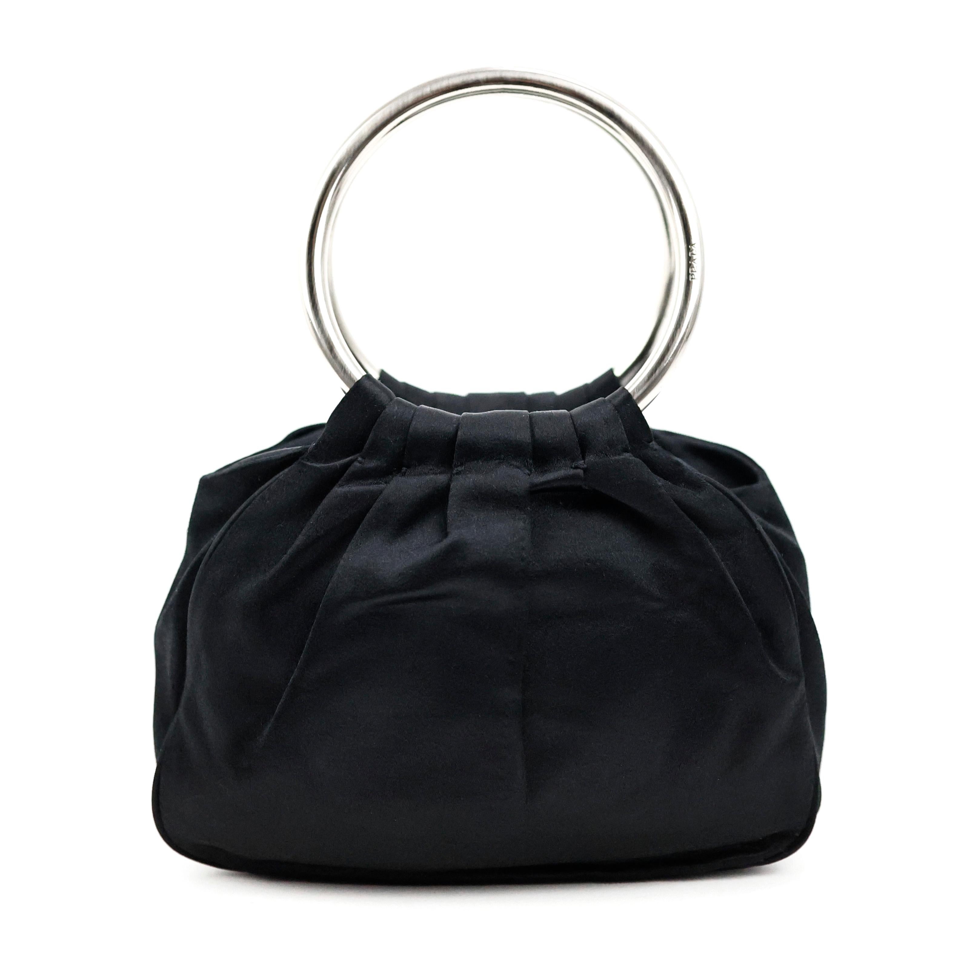 Prada Ring Henkeltasche aus schwarzer Seide, silberne Hardware.

Bedingung:
Wirklich gut. Zu beachten: einige gezogene Fäden auf Seide.

Verpackung/Zubehör:
Staubbeutel, Spiegel.

Abmessungen:
18cm x 13cm x 8cm