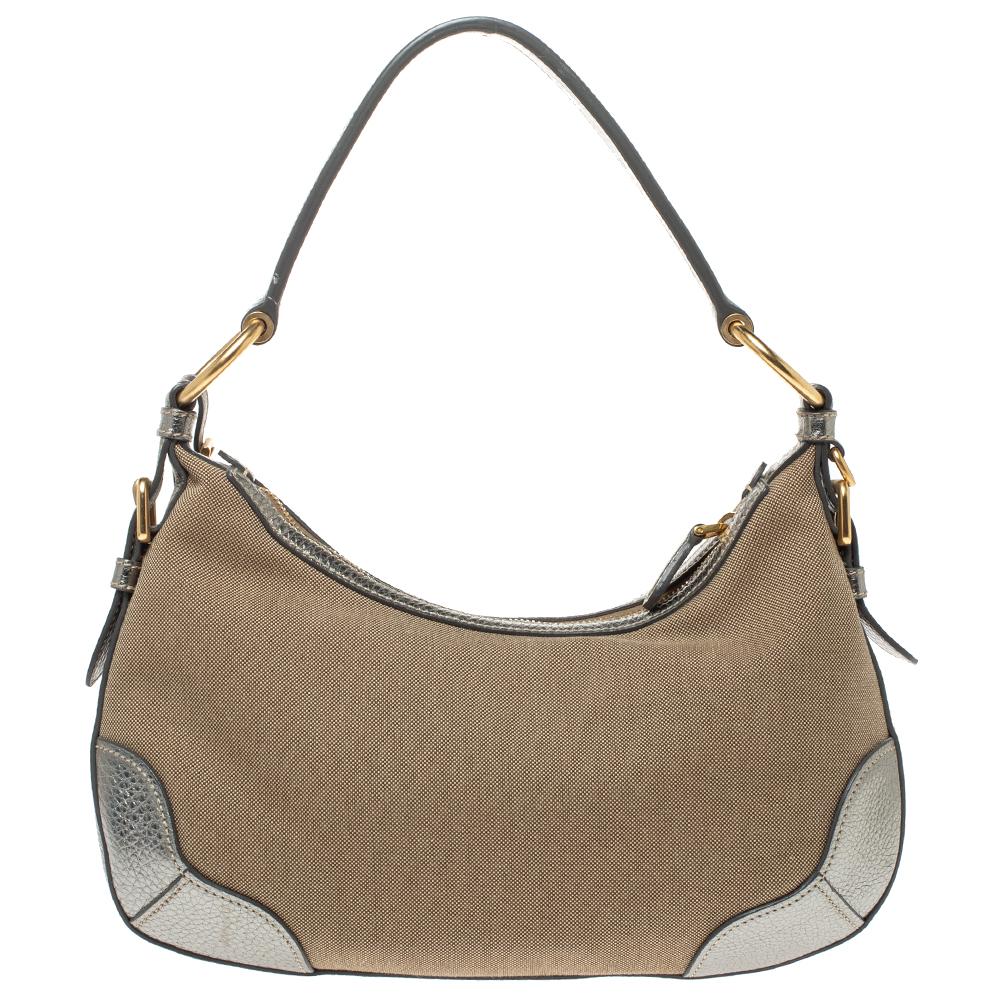 Own this Prada hobo and deliver signature looks instantly. Crafted from logo printed jacquard canvas and leather, it comes in silver & beige hues. It has a single shoulder handle, zip closure, nylon-lined interior and gold-tone hardware
