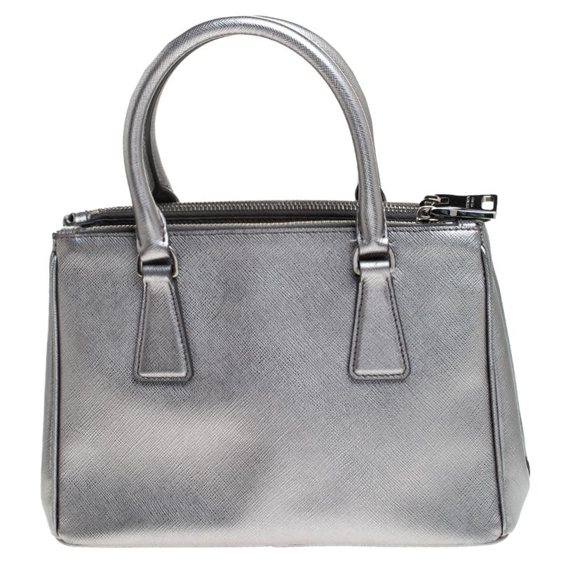 Feminine in shape and grand on design, this Double Zip tote by Prada will be a loved addition to your closet. It has been crafted from leather and styled minimally with silver-tone hardware. It comes with two top handles, two zip compartments and a