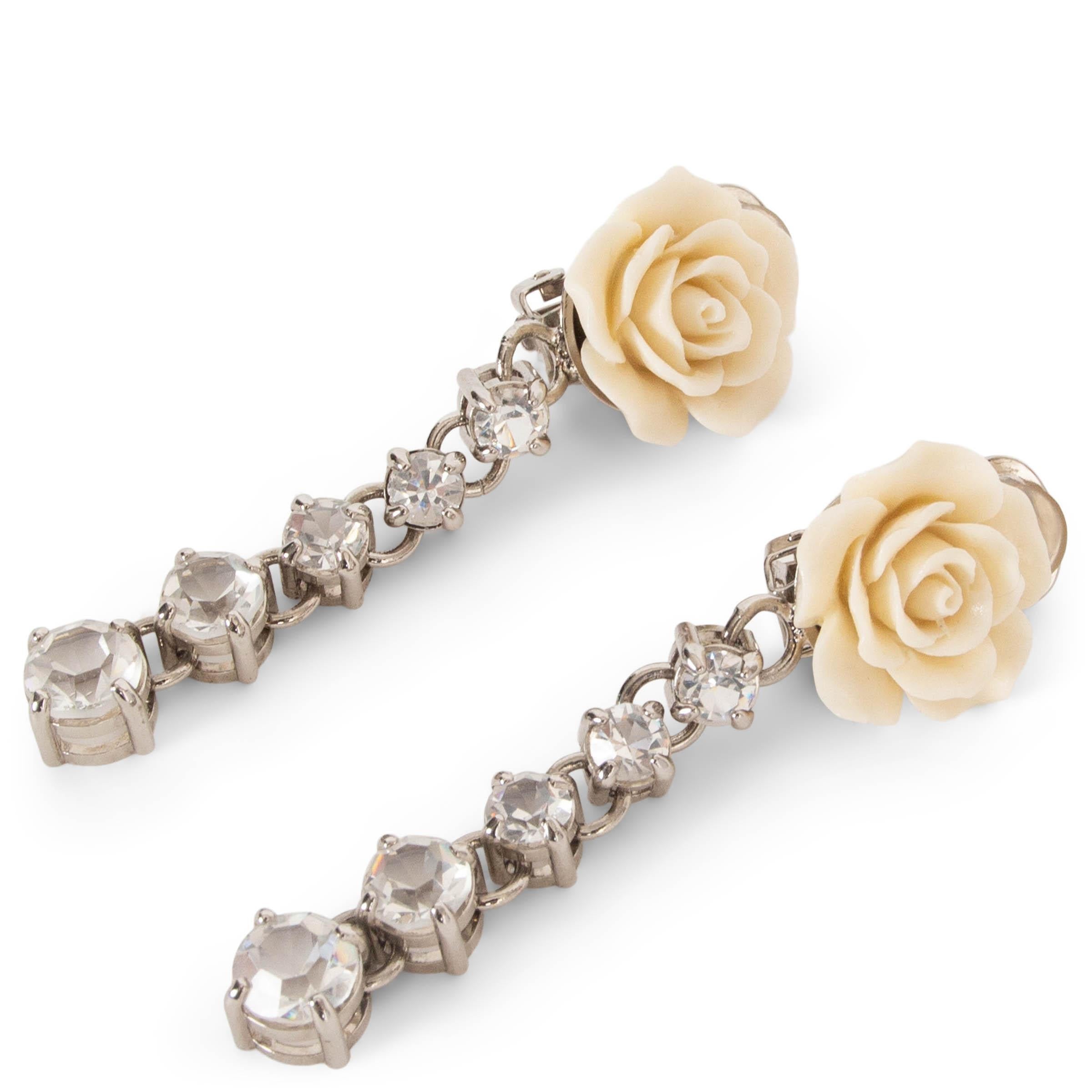 These 100% authentic Prada drop earrings exude romantic elegance, featuring cream resin roses and clear crystal embellishments on delicate silver-tone dangling chains. Designed with a clip-on style, they offer both sophistication and comfort, making