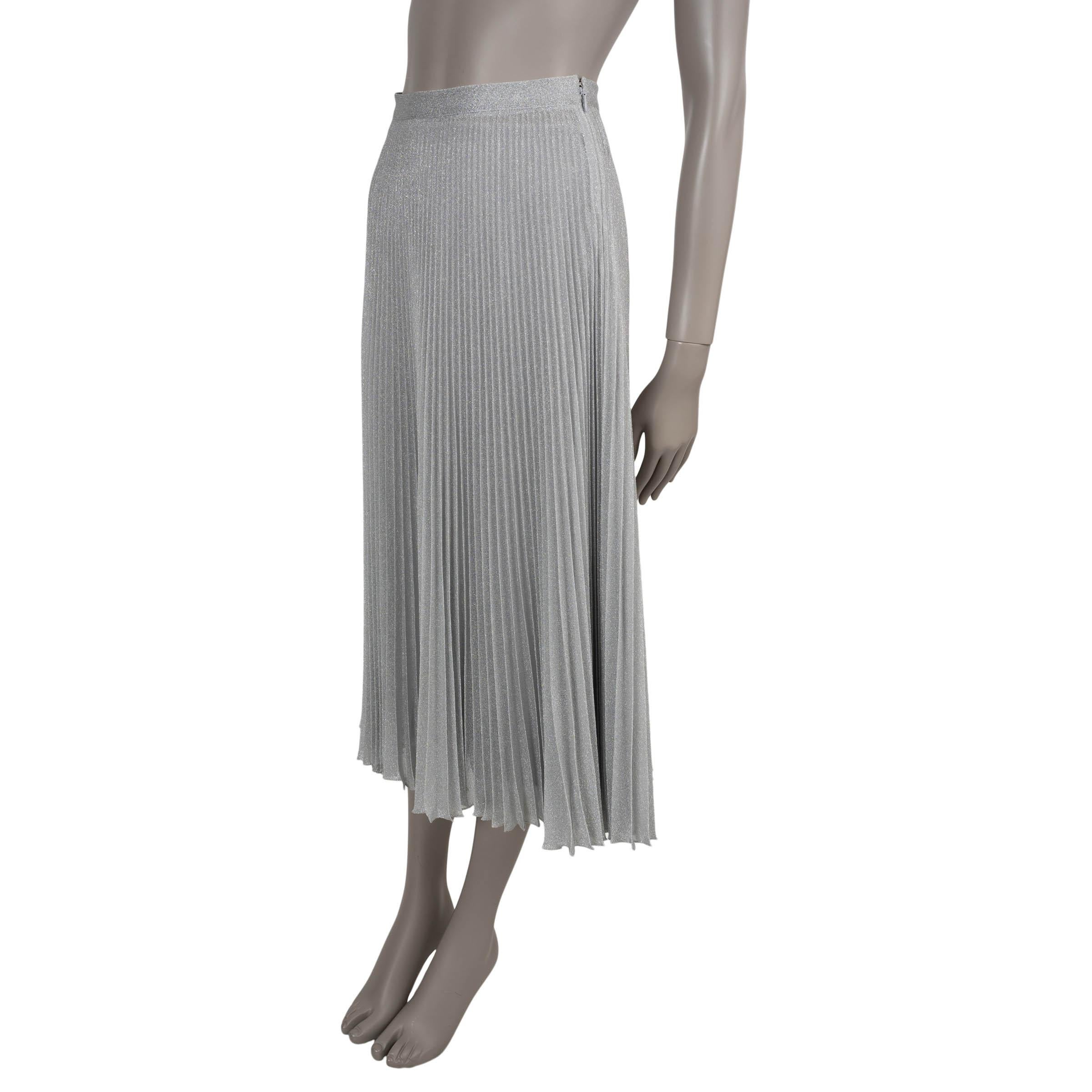This 100% authentic Prada plissé pleated knit skirt in silver lurex viscose (60%), metallic fibre (35%), and polyamide (5%—please note the content tag is missing) features a high-waisted, flared silhouette with elegant midi length. It closes with a
