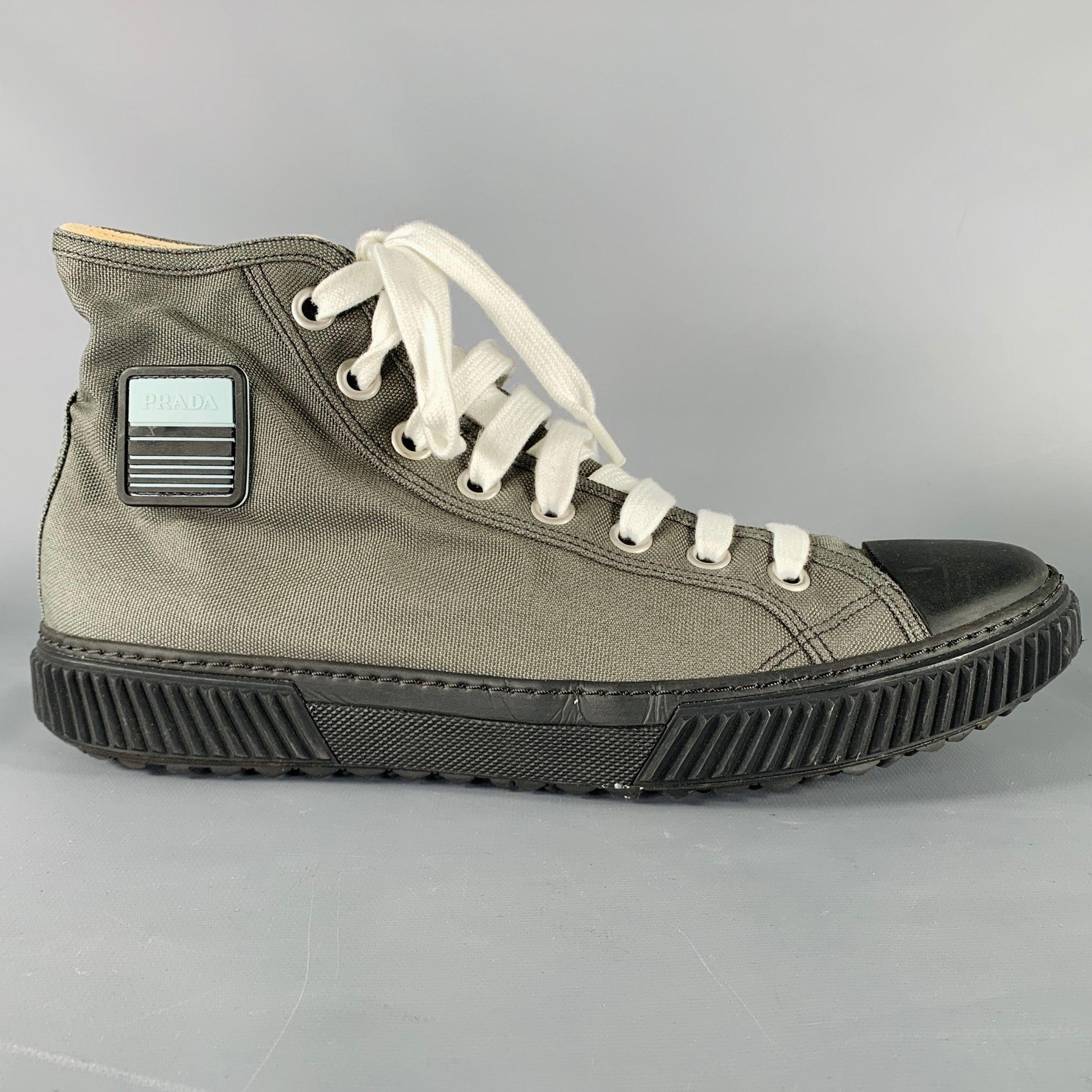 PRADA sneakers
in a grey canvas fabric featuring a high top style, black rubber sole, and lace-up closure.Very Good Pre-Owned Condition. Minor signs of wear. 

Marked:   4T 3218 11 

Measurements: 
  Length: 12 inches Width: 4.5 inches Height: 6.25