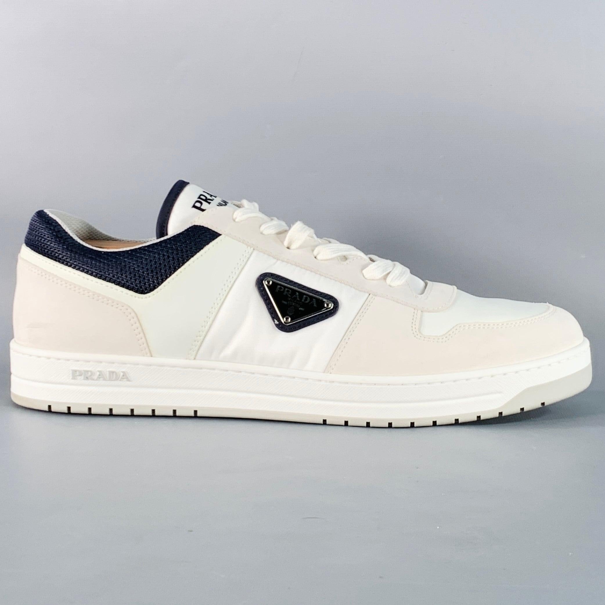 PRADA RE-NYLON sneakers in a white nylon with tonal leather panels and navy mesh featuring a low top style, color block design with black and silver tone metal triangle logo, and lace-up closure. Comes with dust bag. Shoe trees not included. Made in