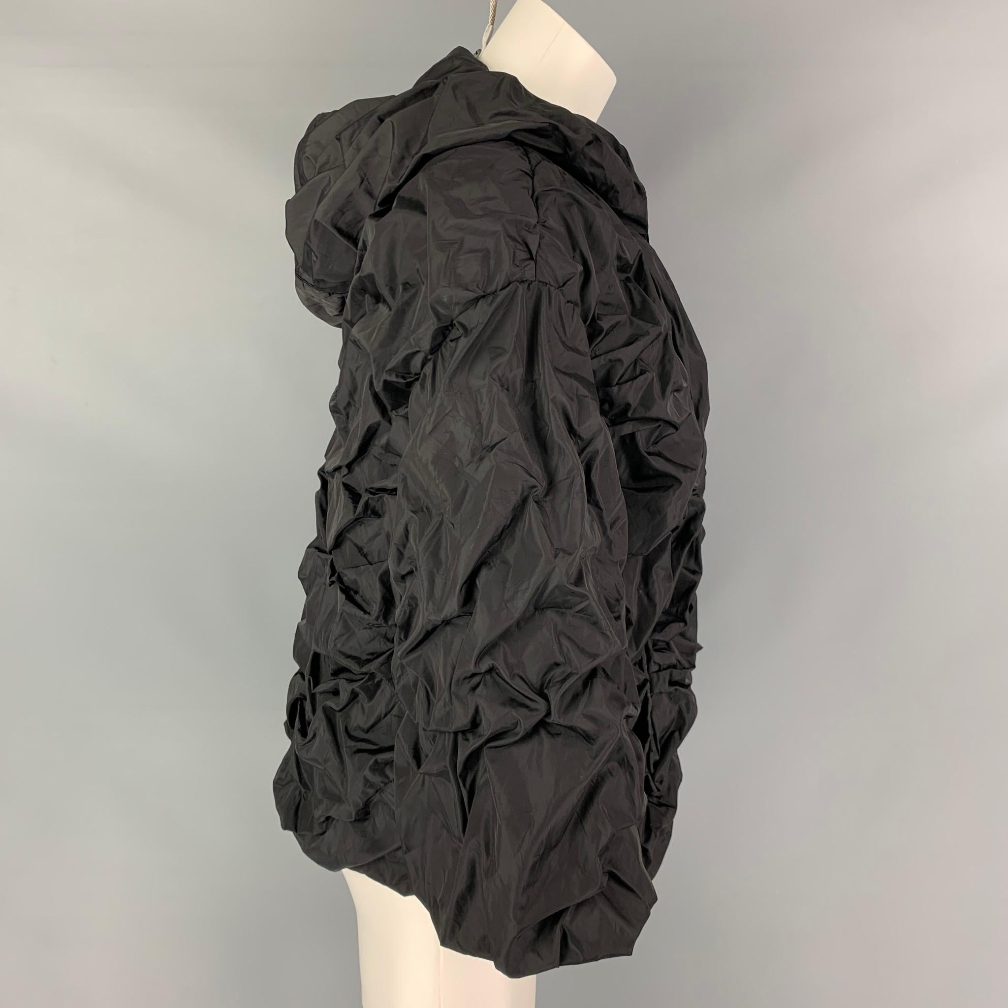 PRADA jacket comes in a black nylon featuring a ruched design, oversized fit, hooded, slit pockets, and a full zipper closure. Made in Italy. 

Very Good Pre-Owned Condition.
Marked: 36

Measurements:

Shoulder: 21 in.
Bust: 42 in.
Sleeve: 16.5