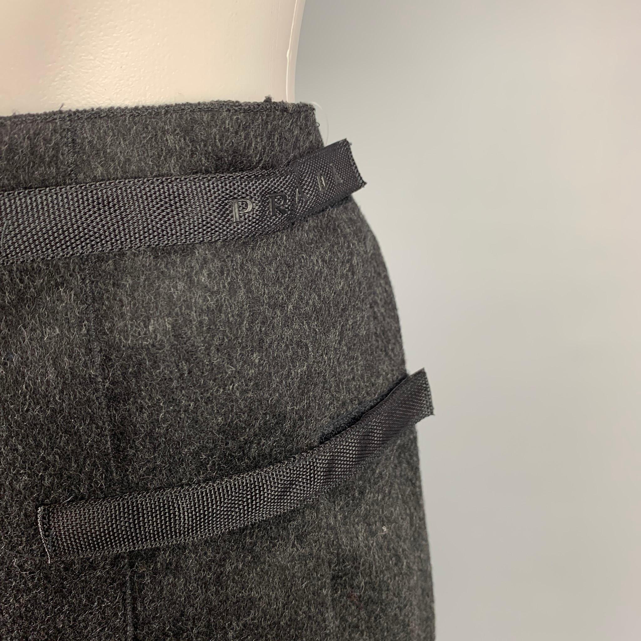 PRADA mini skirt comes in a charcoal virgin wool with a patent leather trim featuring a wrap style, pleated, hook & loop detail, and a snap button closure. Made in Italy. 

Very Good Pre-Owned Condition.
Marked: 38

Measurements:

Waist: 29 in.
Hip: