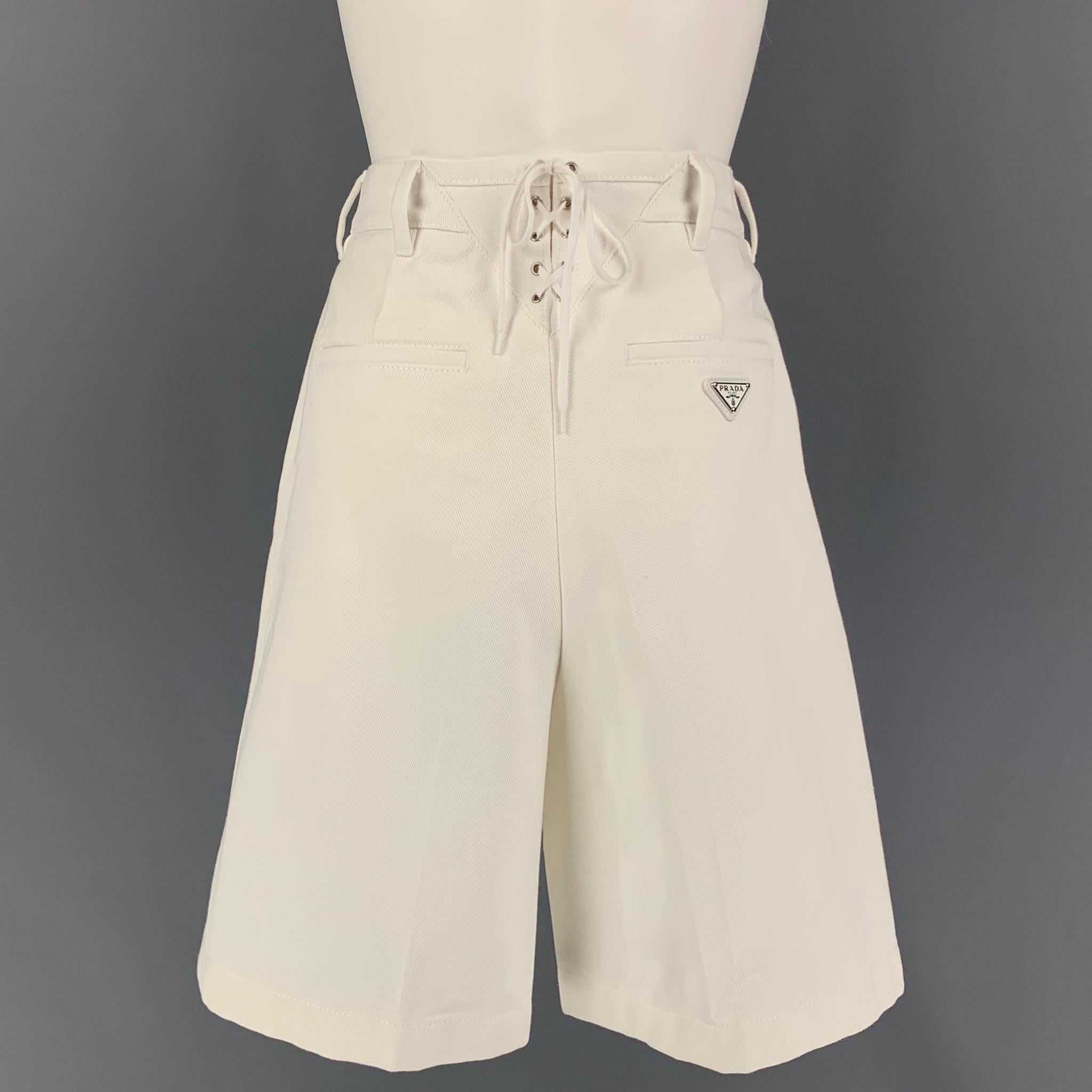 PRADA shorts comes in a white cotton denim featuring a high waist, back self-tie design, logo emblem detail, front, and a zip fly closure. 

Very Good Pre-Owned Condition.
Marked: 38
Original Retail Price: $770.00

Measurements:

Waist: 26 in.
Rise: