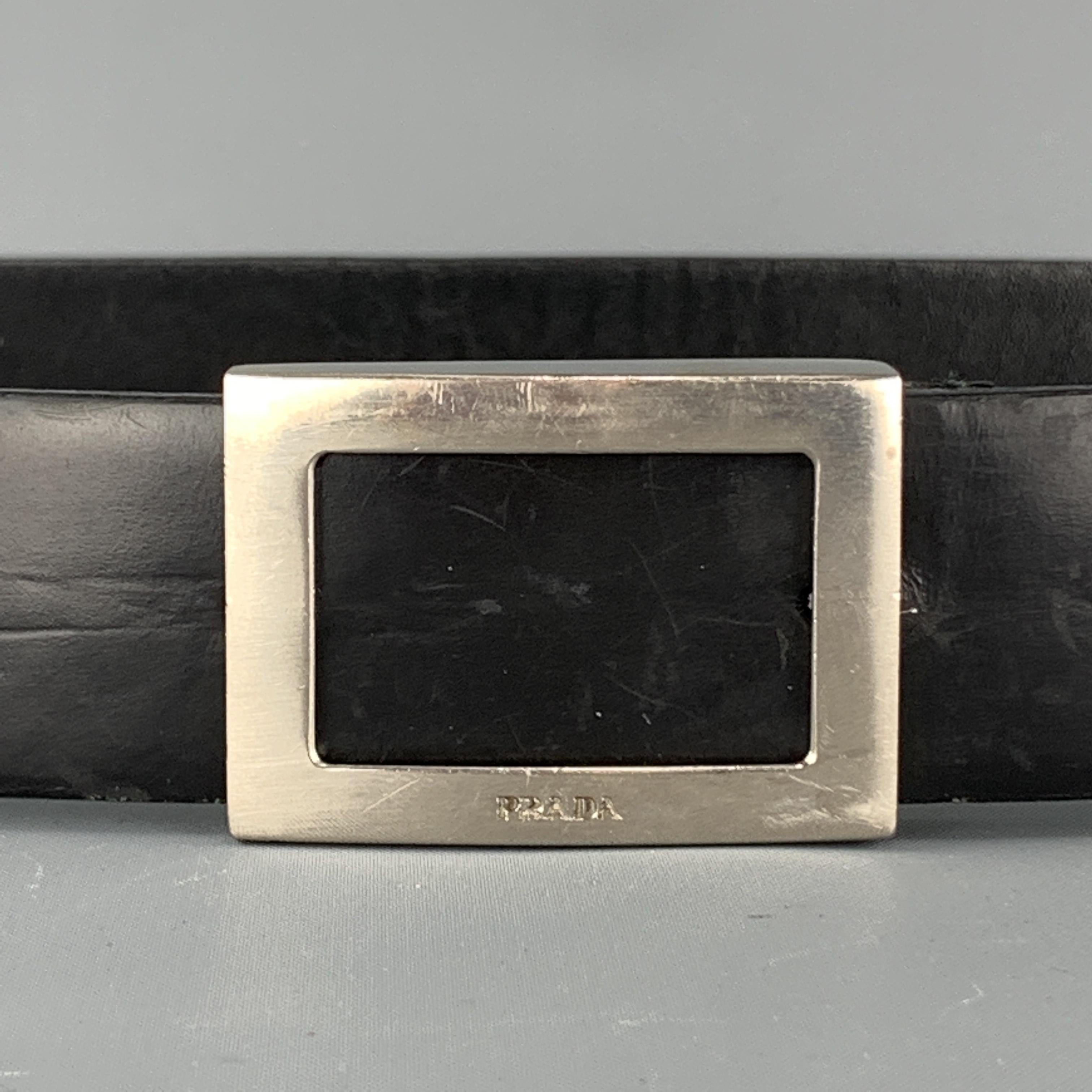 Vintage Prada belt features a black smooth leather strap with a silver tone rectangular cutout, logo engraved buckle. Wear throughout. As-is. Made in Italy.

Fair Pre-Owned Condition.
Marked: 32/80

Length: 38 in.
Width: 1.25 in.
Fits: 29.5 - 33.25