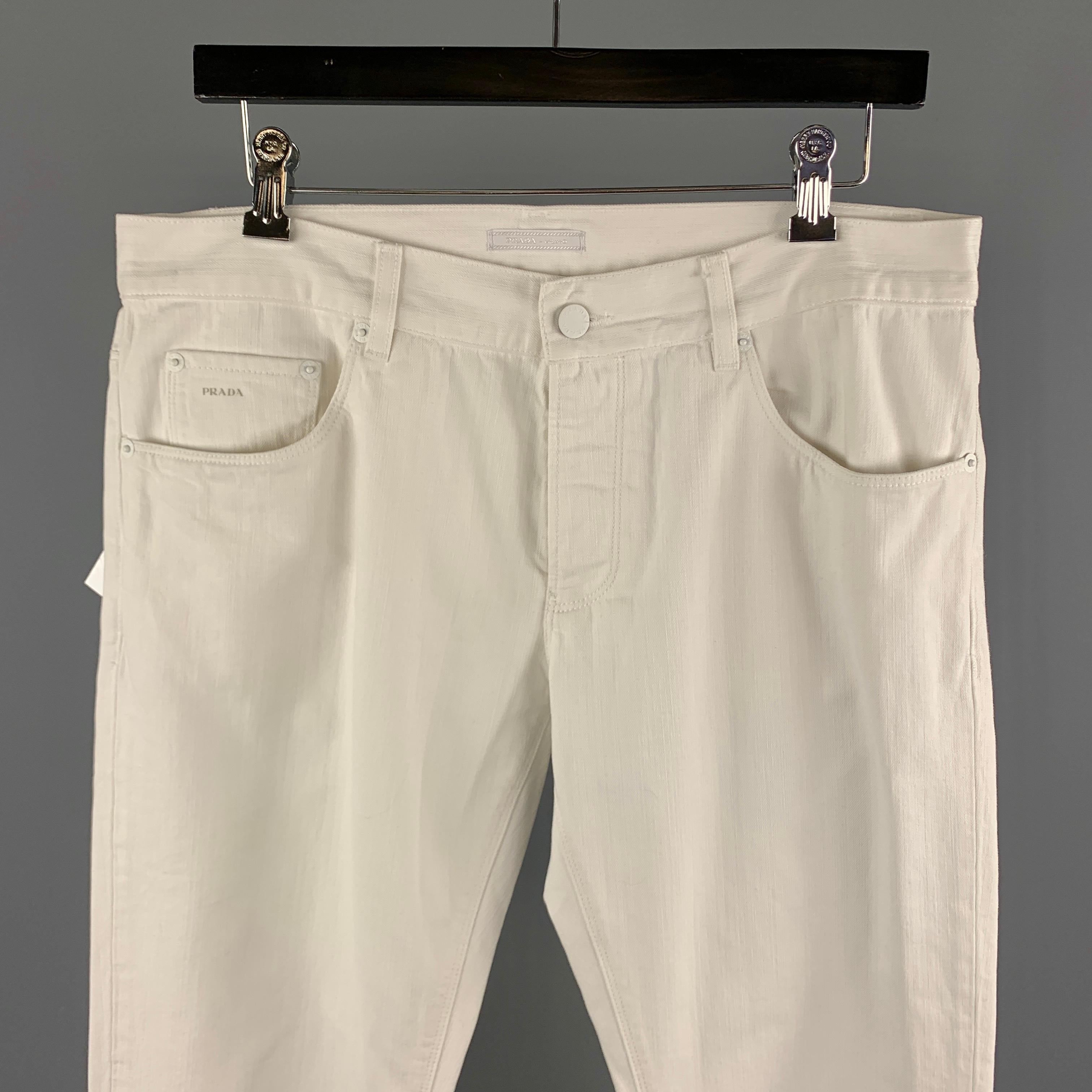 PRADA jeans comes in a white denim featuring a tapered fit and a button fly closure. Made in Romania. 

New With Tags.
Marked: 33

Measurements:

Waist: 33 in. 
Rise: 8 in. 
Inseam: 35 in. 