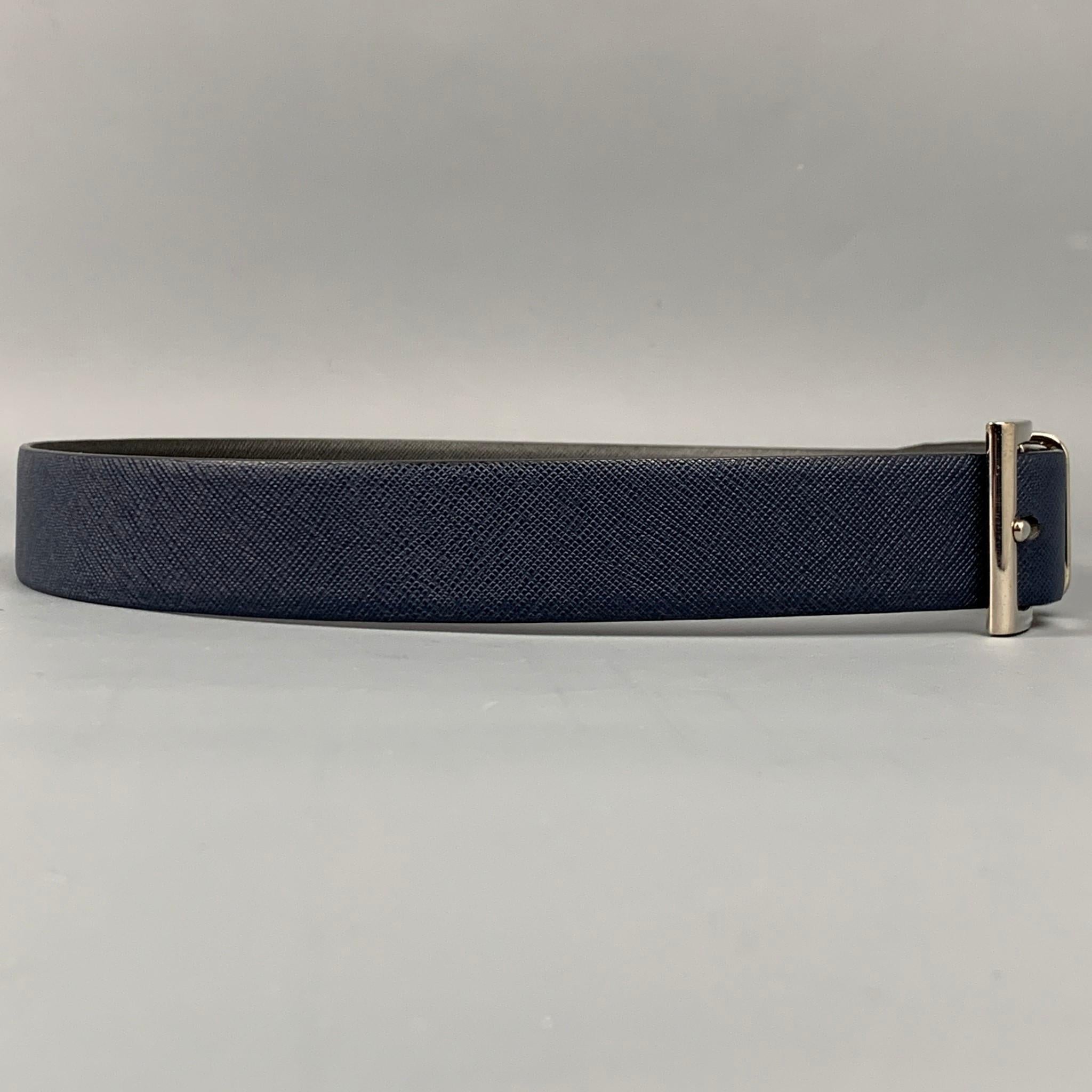 PRADA belt comes in a navy & grey saffiano leather featuring a reversible style and a silver tone buckle. Made in Italy.

Very Good Pre-Owned Condition.
Marked: 85/34 2C5333 6
Original Retail Price: $595.00

Length: 40.5 in.
Width: 1.25 in.
Fits: 32