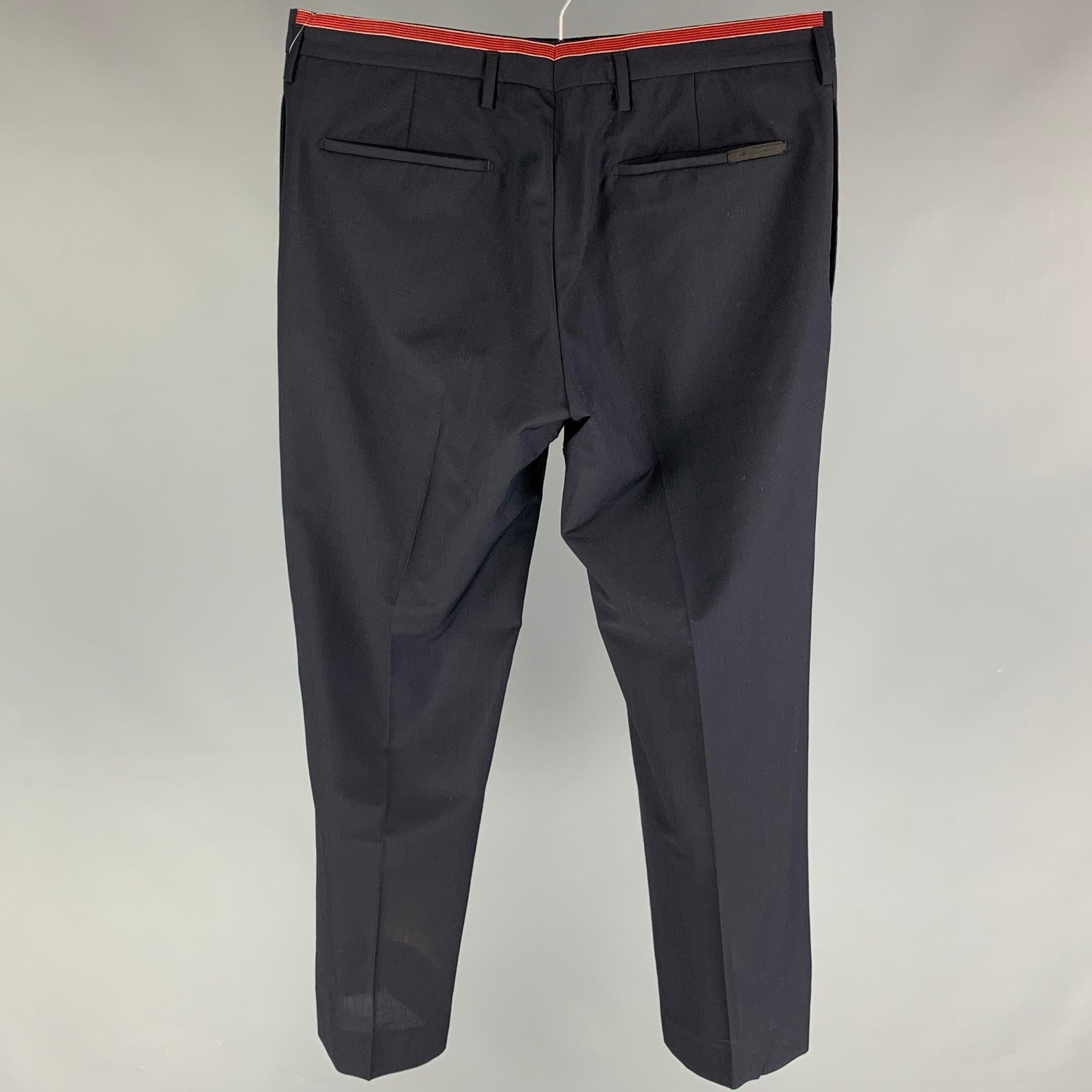 PRADA dress pants comes in a navy virgin wool featuring a flat front, red stripe trim, front tab, and a button fly closure. Made in Italy.
Very Good
Pre-Owned Condition. 

Marked:   50 

Measurements: 
  Waist: 34 inches  Rise: 10 inches  Inseam: 28