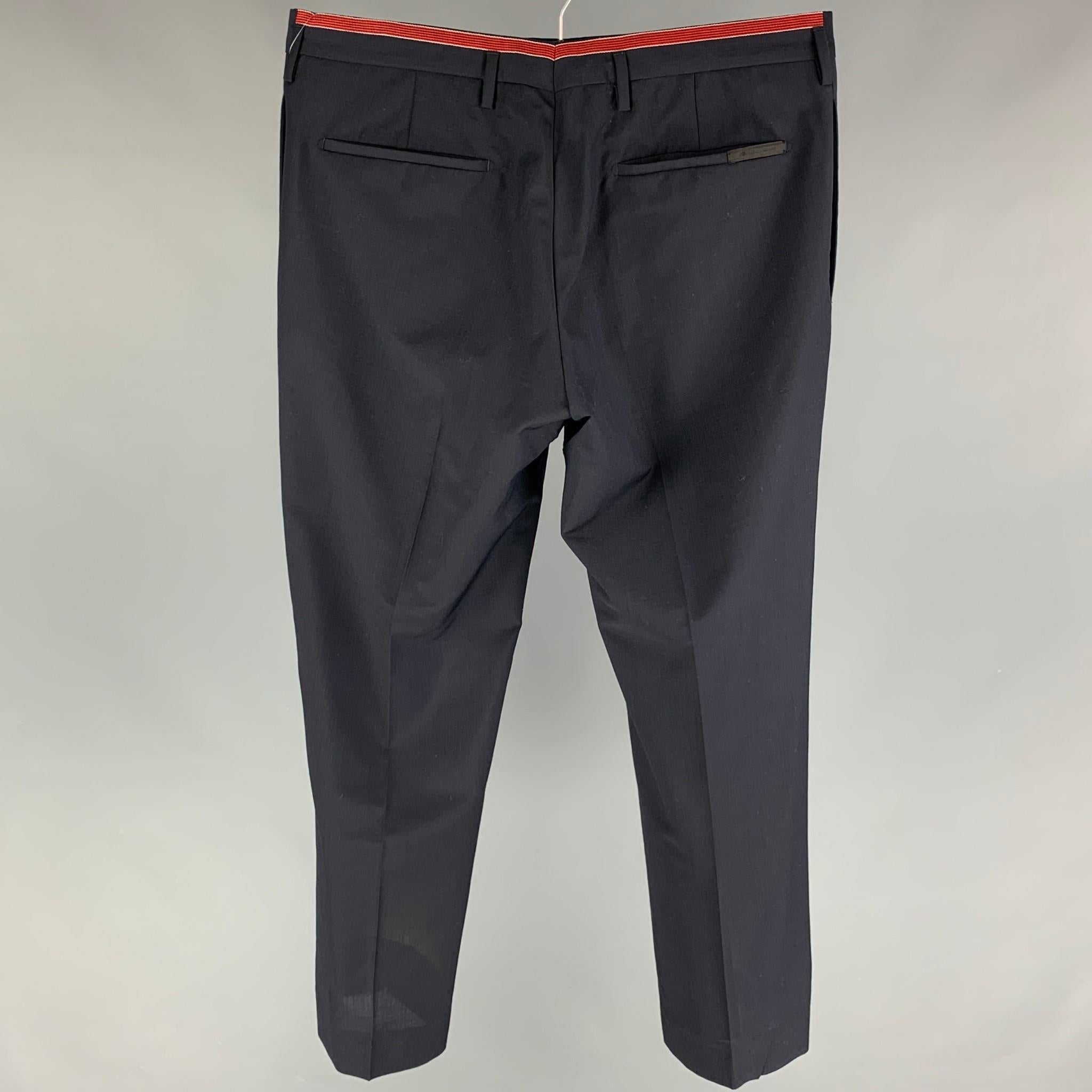 PRADA dress pants comes in a navy virgin wool featuring a flat front, red stripe trim, front tab, and a button fly closure. Made in Italy. 

Very Good Pre-Owned Condition.
Marked: 50

Measurements:

Waist: 34 in.
Rise: 10 in.
Inseam: 28 in. 