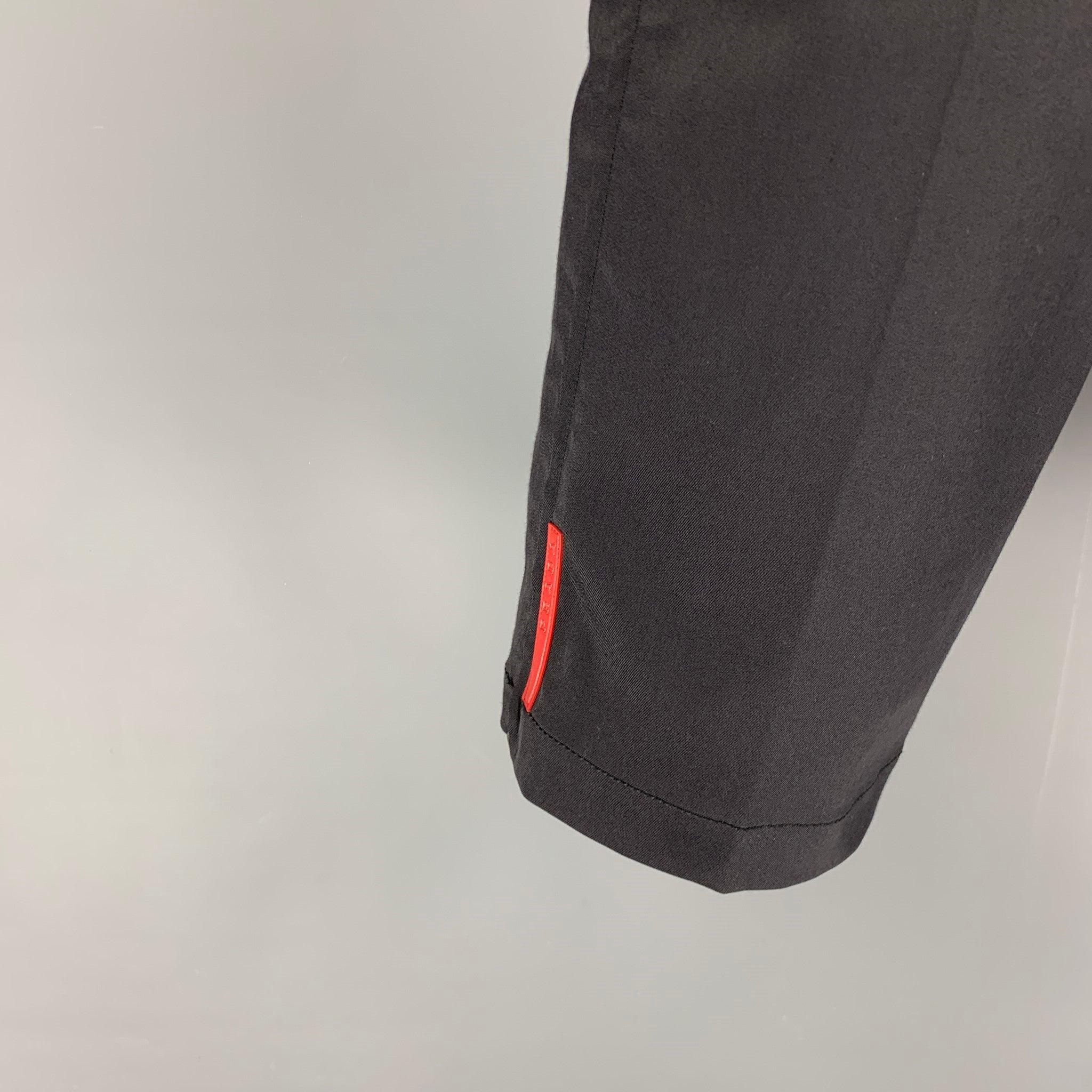 PRADA dress pants comes in a black cotton blend featuring a flat front, zipped cuffs, red logo detail, front tab, and a button fly closure. Made in Italy.Excellent
Pre-Owned Condition. Fabric tag removed.  

Marked:   Size tag removed. 