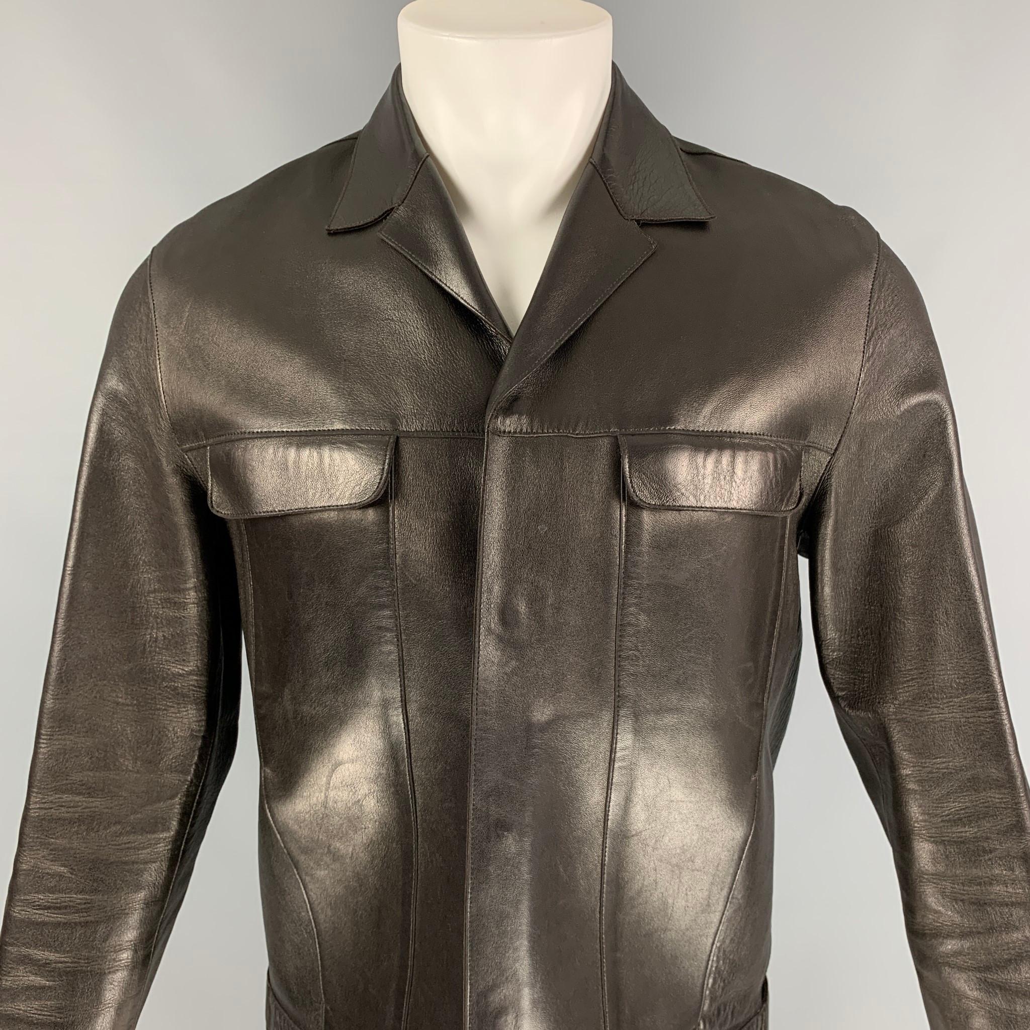 PRADA jacket comes in a dark brown leather featuring a notch lapel, front pockets, and a hidden snap button closure. Made in Italy. 

Excellent Pre-Owned Condition.
Marked: 38

Measurements:

Shoulder: 18 in.
Chest: 40 in.
Sleeve: 26 in.
Length: