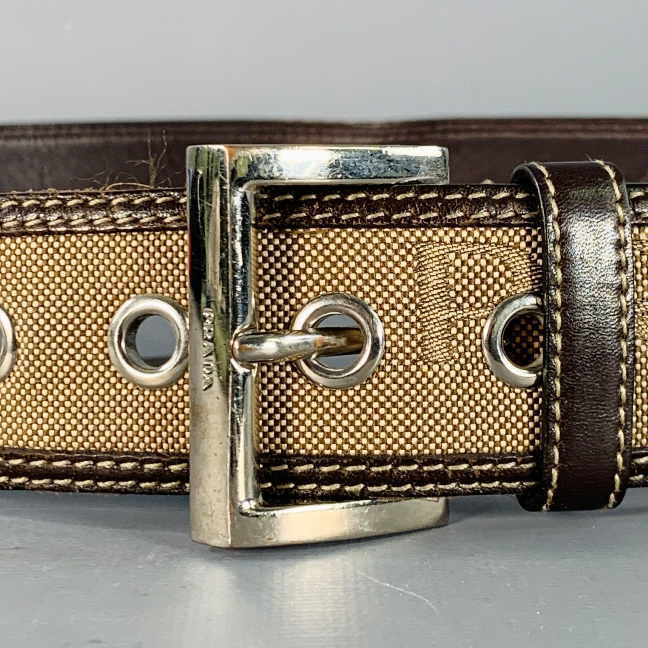 PRADA
cintura in tela marrone con rifiniture in pelle marrone, motivo logo testurizzato e fibbia in metallo argentato. Ottimo stato usato. Segni di usura sui bordi. 

Contrassegnato:   2C 3612 1Lunghezza: 42,5 pollici Larghezza: 1,5 pollici Adatta: