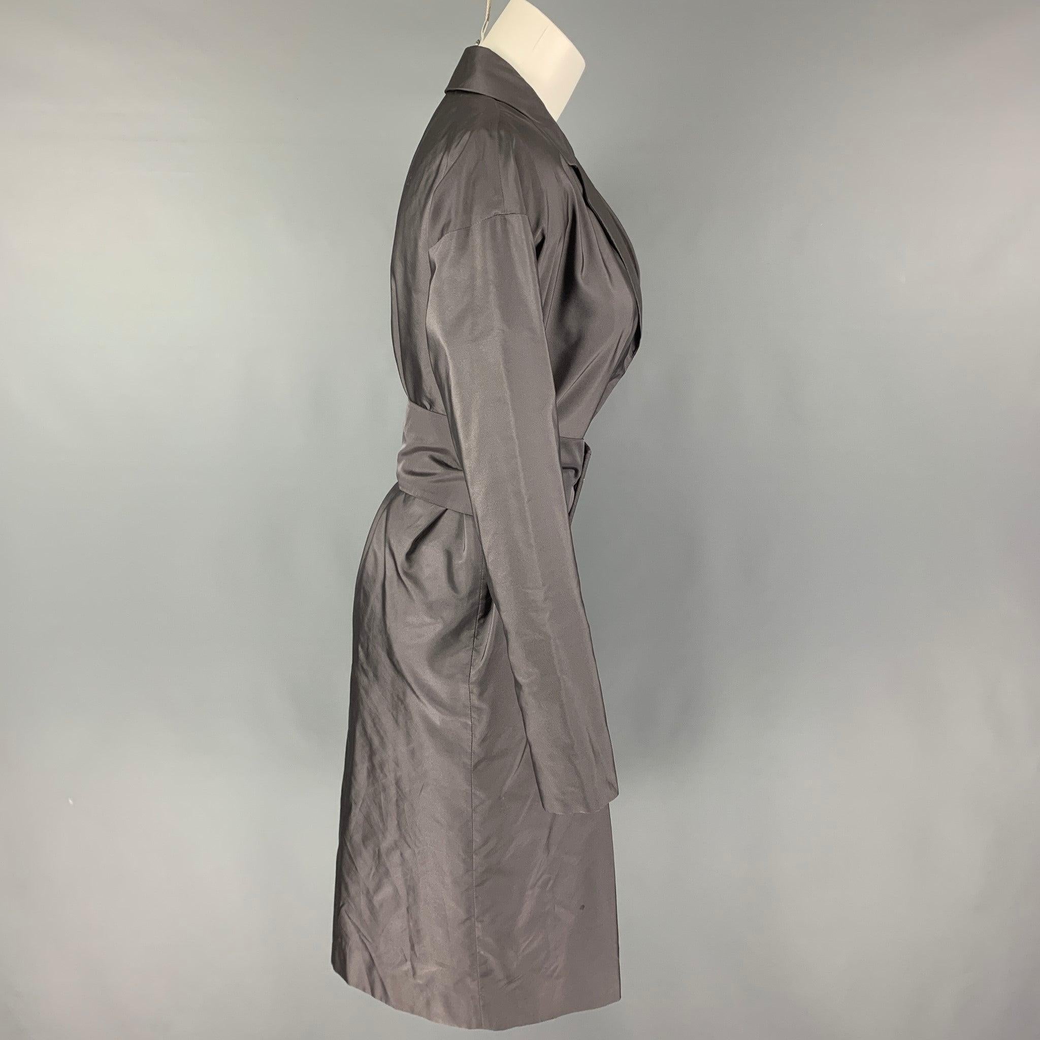 PRADA coat comes in a grey silk featuring a notch lapel, belted, and a hidden snap button closure. Made in Italy.
Very Good
Pre-Owned Condition. 

Marked:  40 

Measurements: 
 
Shoulder: 21.5 inches Bust: 40 inches Sleeve:
20.5 inches Length: 41