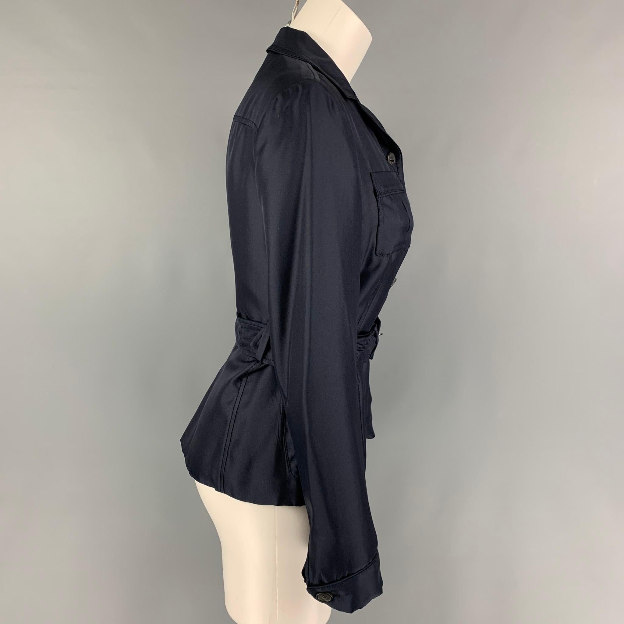 PRADA jacket comes in a navy silk featuring a belted detail, front pockets, notch lapel, and a buttoned closure. Made in Italy. 

Very Good Pre-Owned Condition.
Marked: 40

Measurements:

Shoulder: 16 in.
Bust: 34 in.
Sleeve: 24.5 in.
Length: 23 in. 