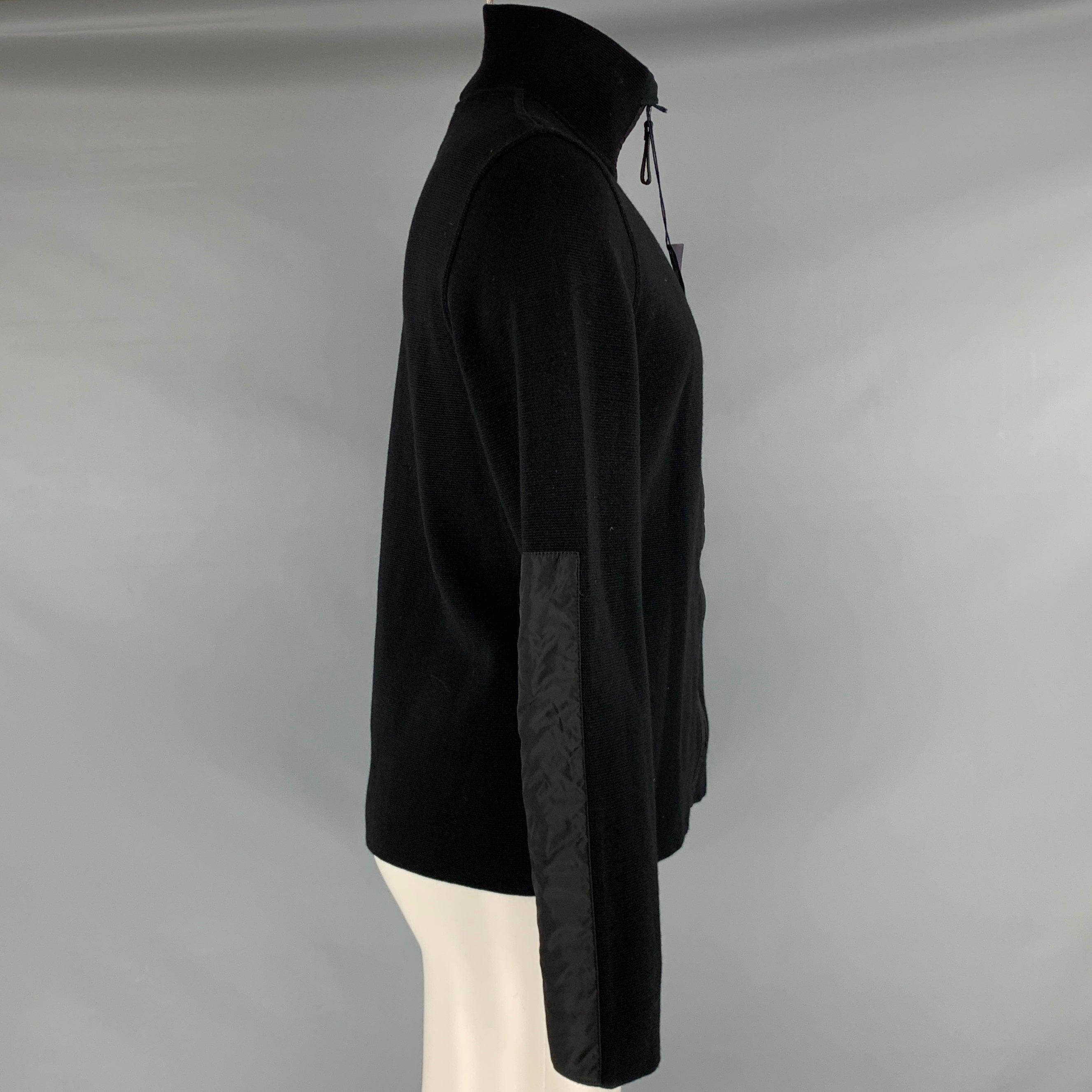 PRADA jacket in a black wool fabric with nylon trim, featuring a waffle knit style, blouson sleeves, and zip up closure. Made in Romania.Very Good Pre-Owned Condition with Tags. Small tear on back. 

Marked:   50 

Measurements: 
 
Shoulder: 16.5