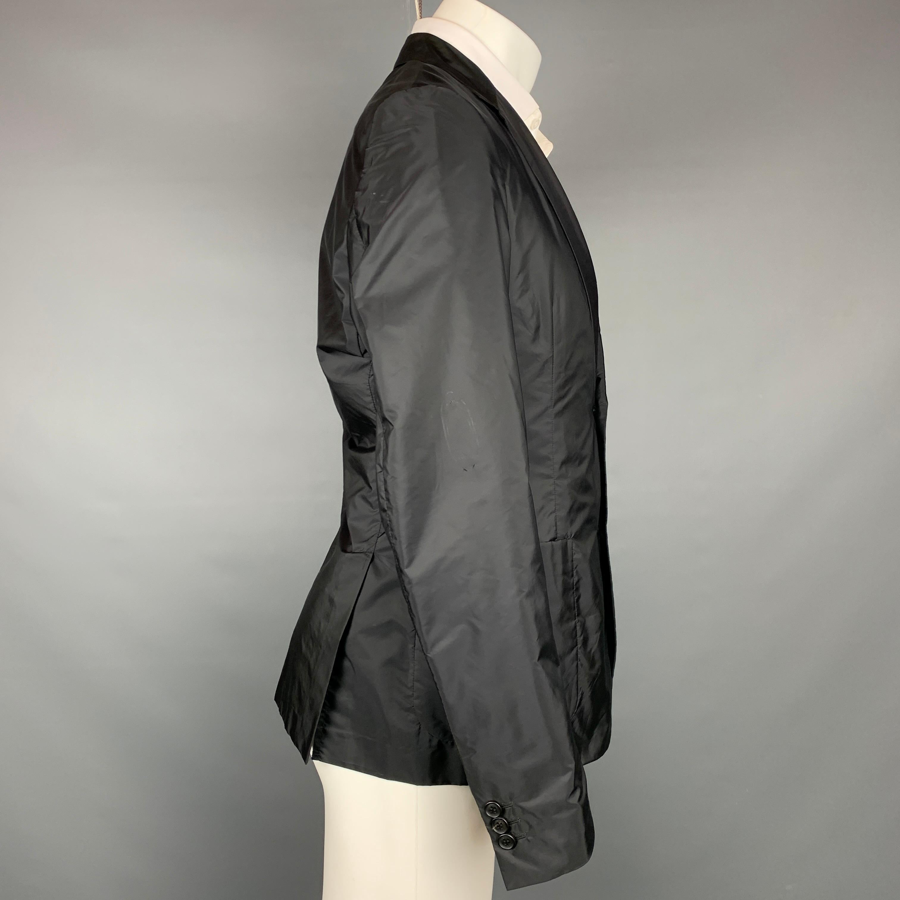 PRADA sport coat comes in a black nylon with a half liner featuring a notch lapel, patch pockets, and a two button closure. 

Very Good Pre-Owned Condition.
Marked: 50

Measurements:

Shoulder: 17.5 in.
Chest: 40 in.
Sleeve: 26.5 in.
Length: 27.5