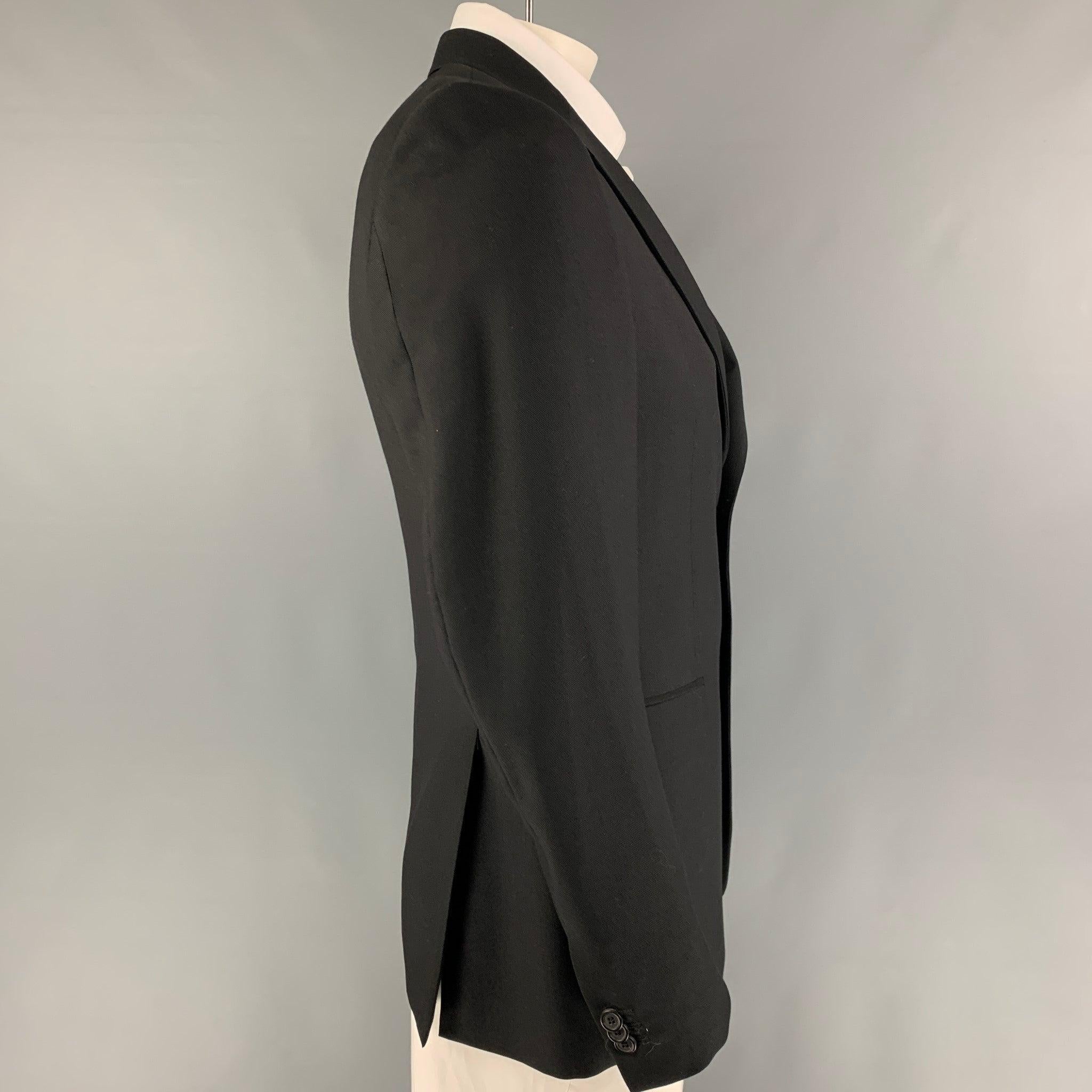PRADA sport coat comes in a black wool with a full liner featuring a notch lapel, flap pockets, double back vent, and a double button closure.Very Good
Pre-Owned Condition. 

Marked:   50 R  

Measurements: 
 
Shoulder: 18 inches  Chest: 40 inches 