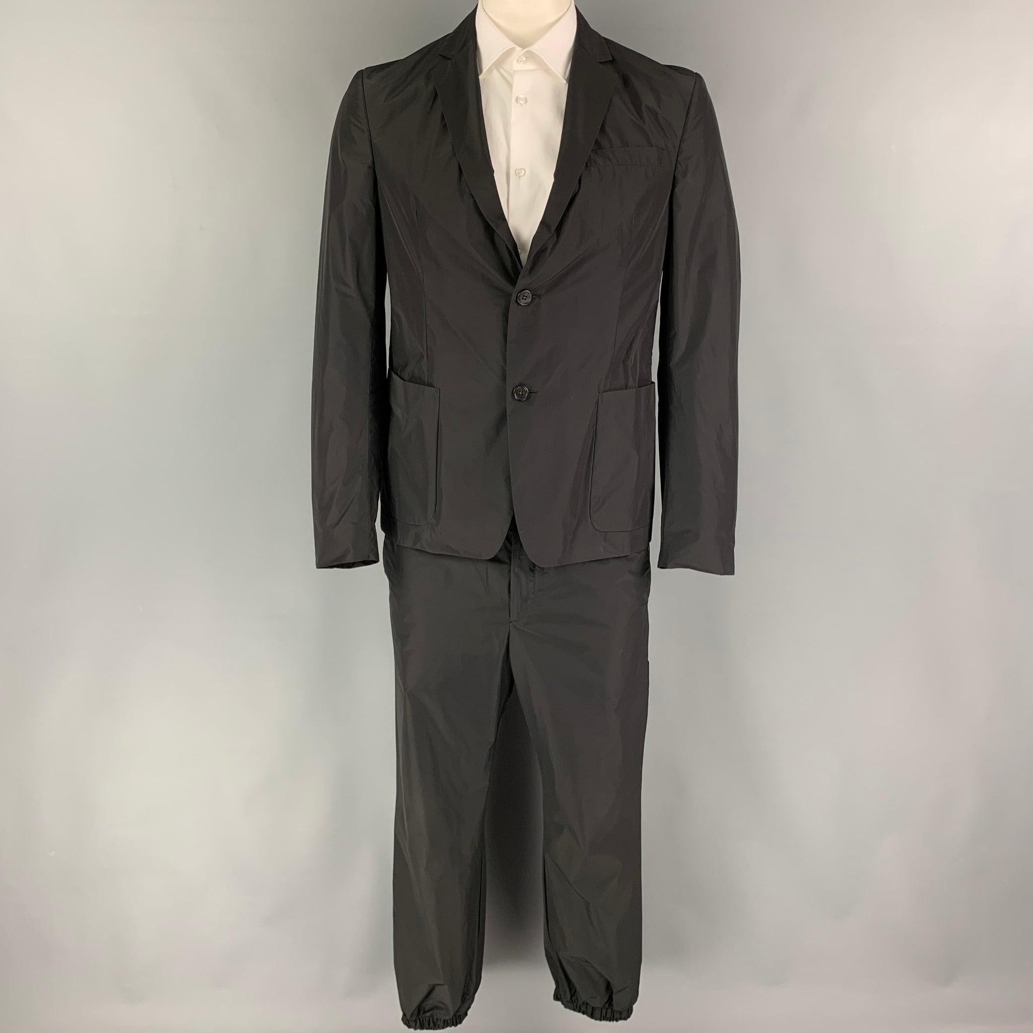 PRADA
suit comes in a black polyester with a half mesh liner and includes a single breasted, double button sport coat with a notch lapel and matching flat front pants. Excellent Pre-Owned Condition. 

Marked:   52 

Measurements: 
  -JacketShoulder:
