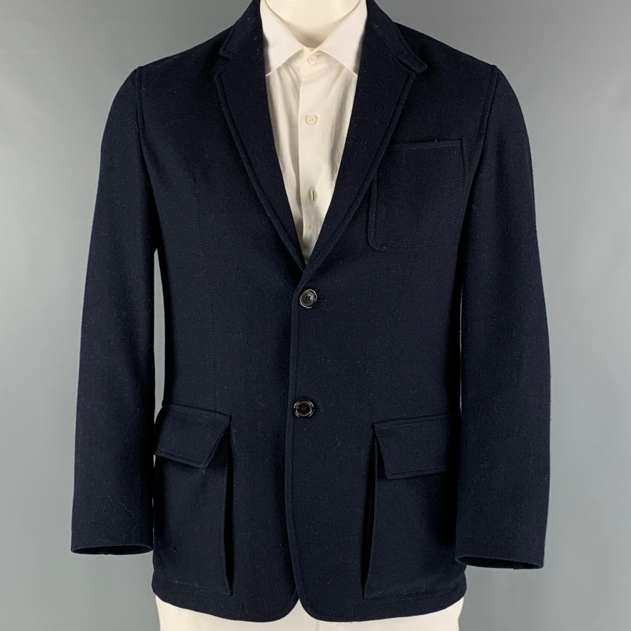 PRADA sport coat comes in a navy wool woven material with a full liner featuring a notch lapel, patch pockets, single back vent, and a double button closure.

Excellent Pre-Owned Condition.
Marked: 52

Measurements:

Shoulder: 18 in.
Chest: 40