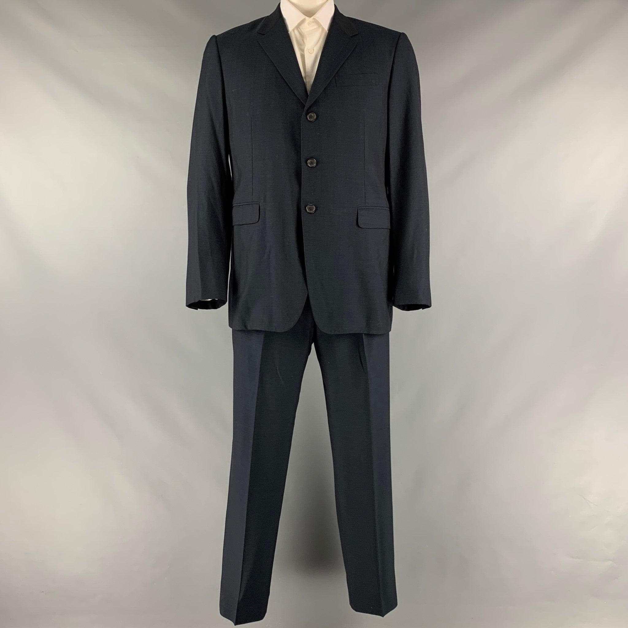 PRADA suit comes in a navy virgin wool and silk woven material with a full line and includes a single breasted, three button sport coat with a notch lapel and matching flat front trousers. Very Good Pre-Owned Condition. 

Marked:   44