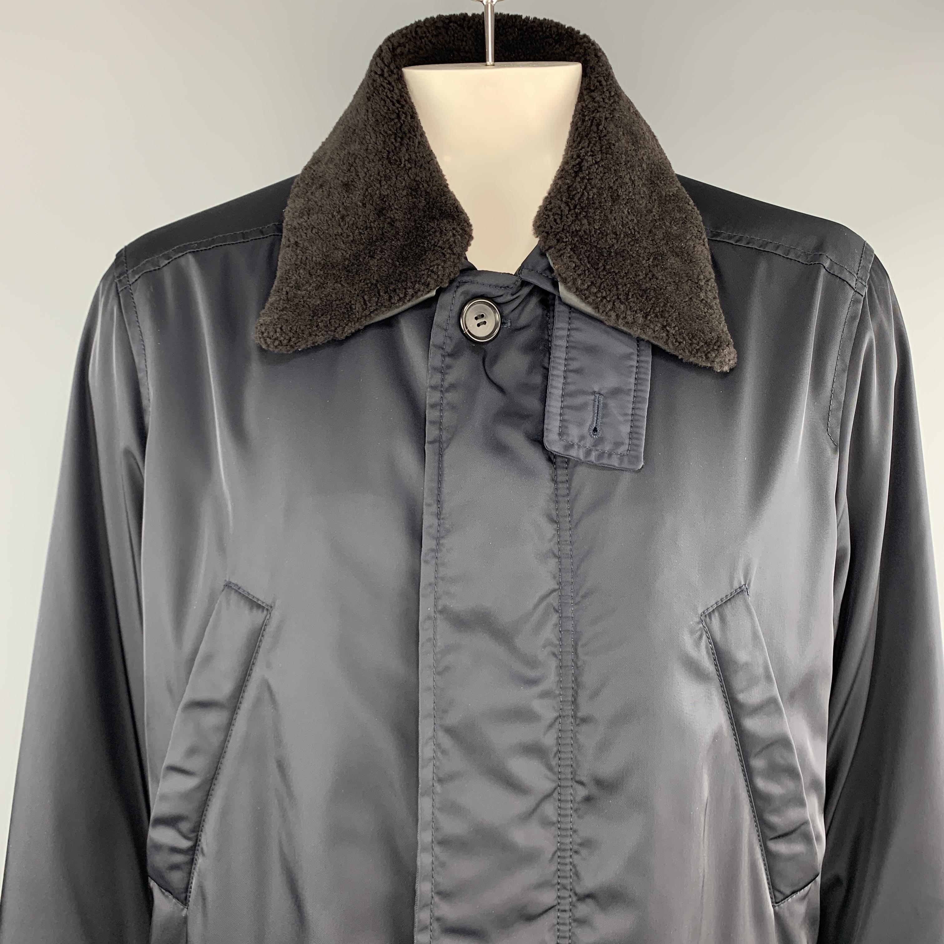 PRADA over coat comes in navy blue nylon twill with a zip and button hidden placket closure front, slanted zip and flap pockets, ribbed cuff sleeves, and detachable brown lamb shearling fur collar. Made in Italy.

Very Good Pre-Owned