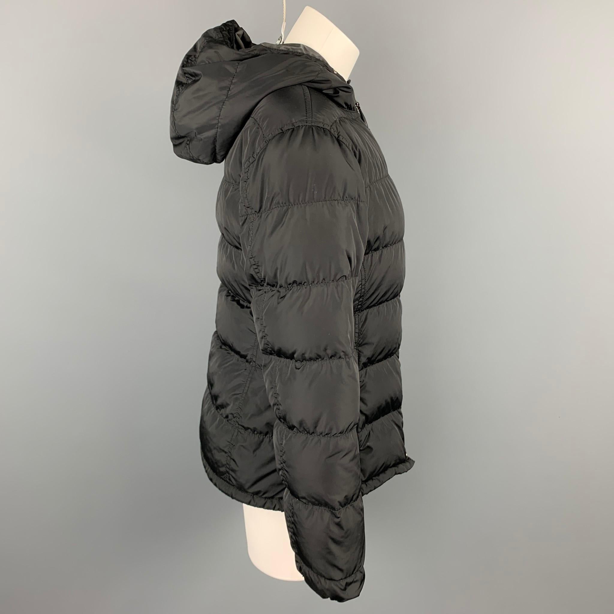 PRADA jacket comes in a black quilted nylon featuring a hooded style, zipper pockets, inner waistband, and a zip up closure. Moderate wear. Made in Italy.

Good Pre-Owned Condition.
Marked: 42

Measurements:

Shoulder: 17 in.
Bust: 38 in.
Sleeve: 24