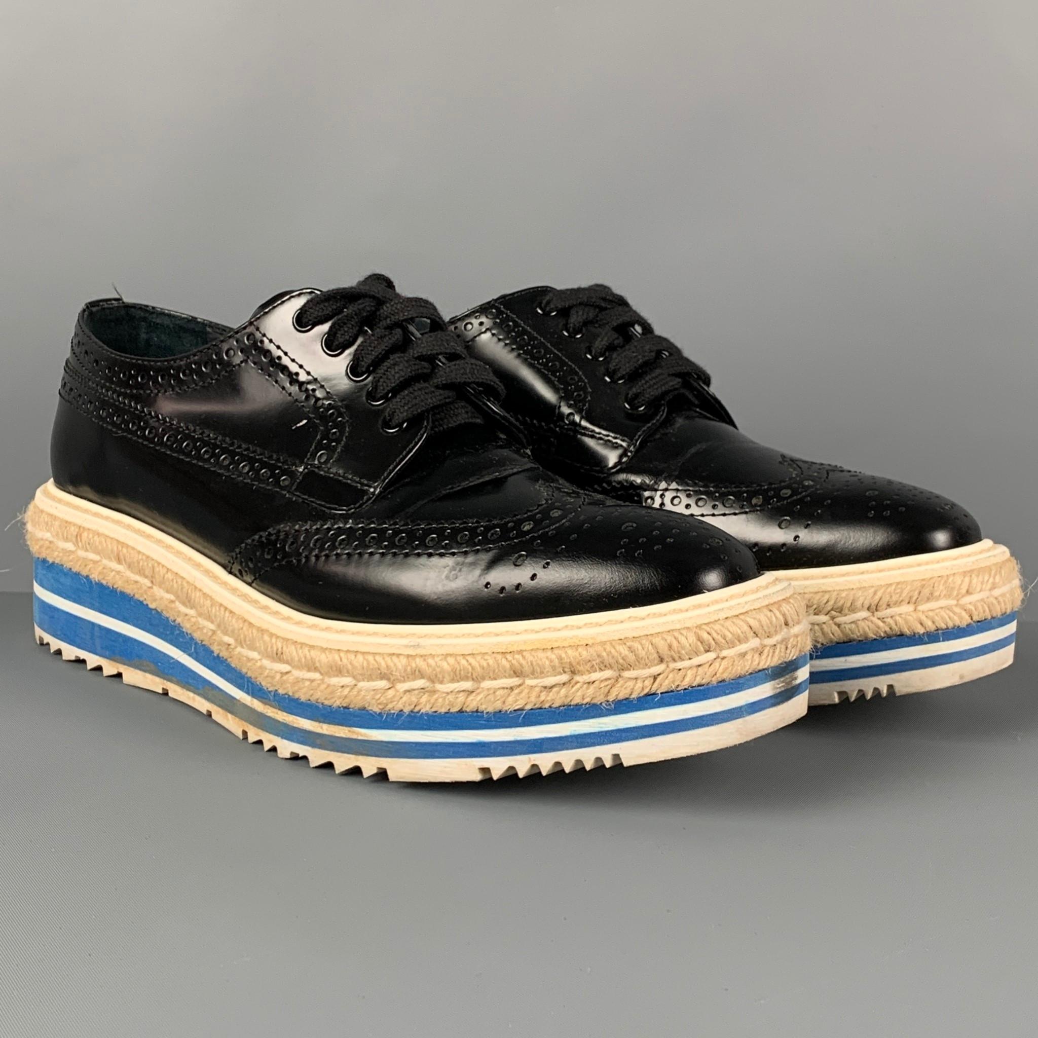 PRADA shoes comes in a black perforated leather featuring a wingtip style, square toe, and a jute trim platform sole. Made in Italy. 

Very Good Pre-Owned Condition.
Marked: 36.5

Outsole: 10.5 in. x 3.5 in. 