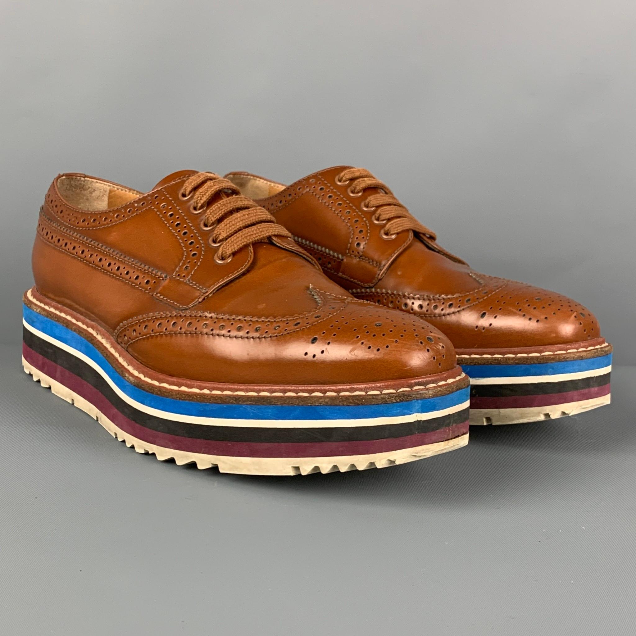 PRADA shoes comes in a tan perforated leather featuring a wingtip style, rubber platform sole, and a lace up closure. Made in Italy. 

Very Good Pre-Owned Condition.
Marked: 36

Outsole: 10.5 x 3.5 in. 