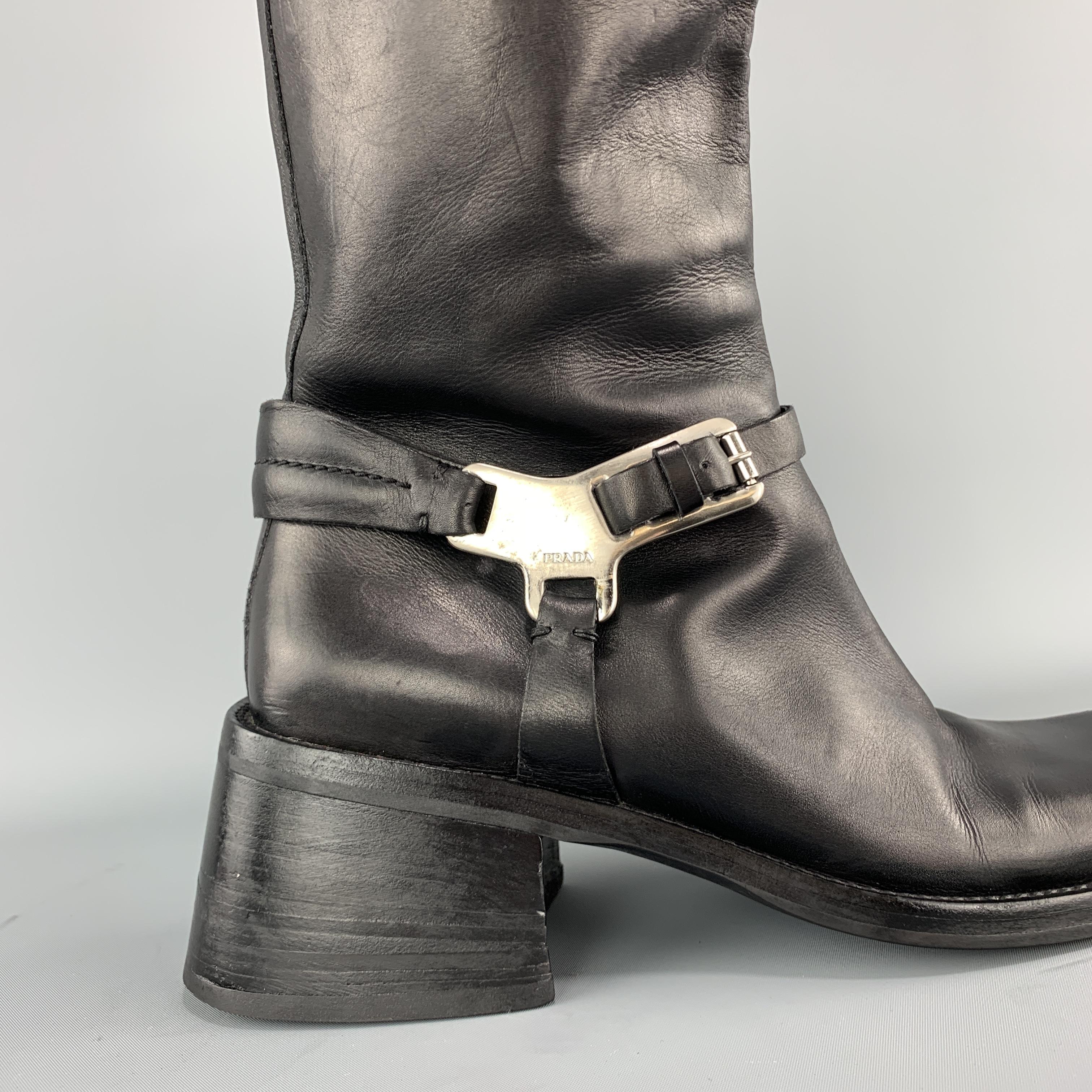 Vintage 1990's PRADA knee high boots come in smooth black leather with a stacked chunky heel and silver tone metal detailed harness. Made in Italy.

Very Good Pre-Owned Condition.
Marked: IT 40

Width: 4 in.
Heel: 2.5 in.
Length: 15.5 in.
Ankle: 12