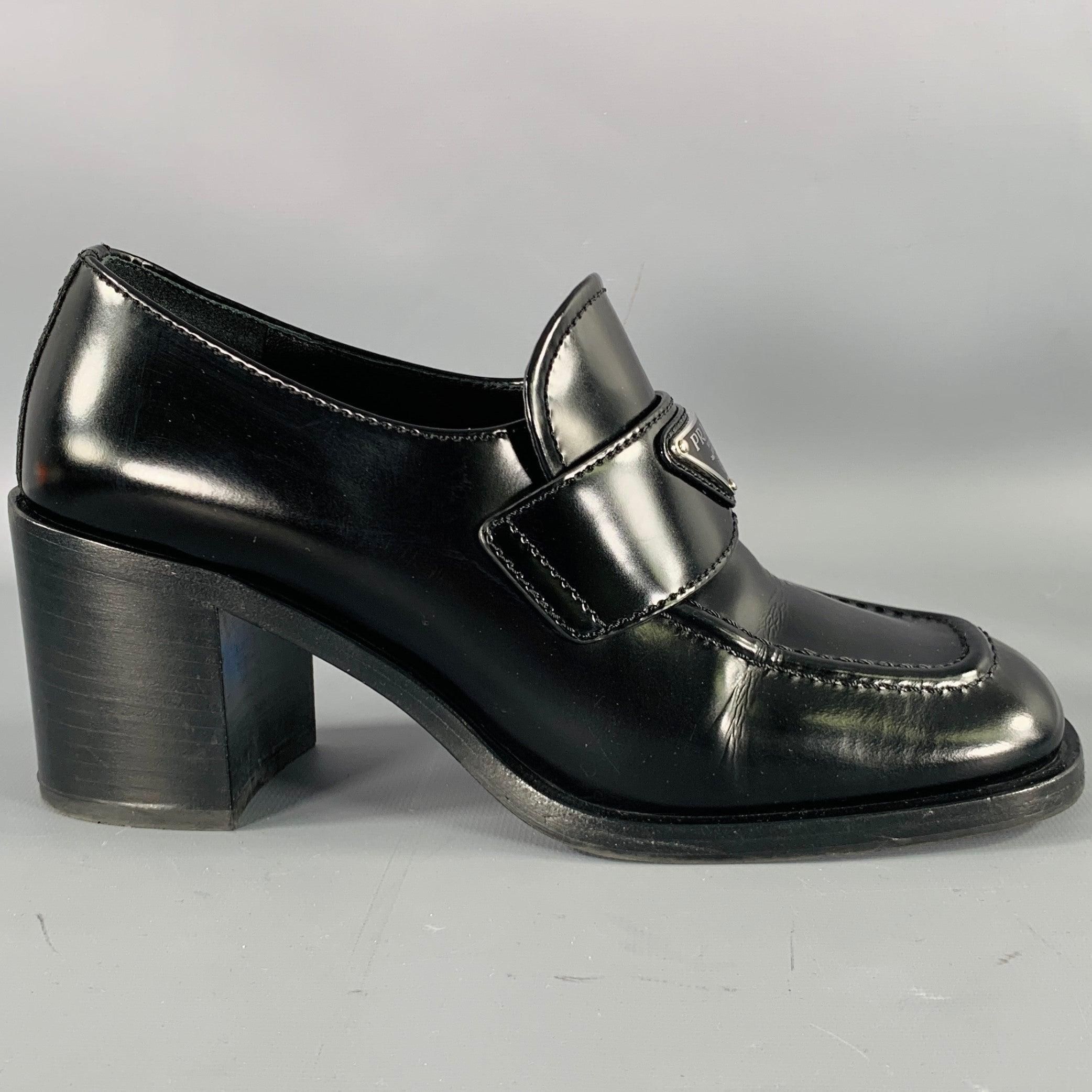 PRADA pumps
in a black leather featuring a penny loafer style, silver tone metal PRADA logo, and chunky sole. Made in Italy.Excellent Pre-Owned Condition. 

Marked:   37.5 

Measurements: 
  Heel: 2.75 inches  
  
  
 
Sui Generis Reference: