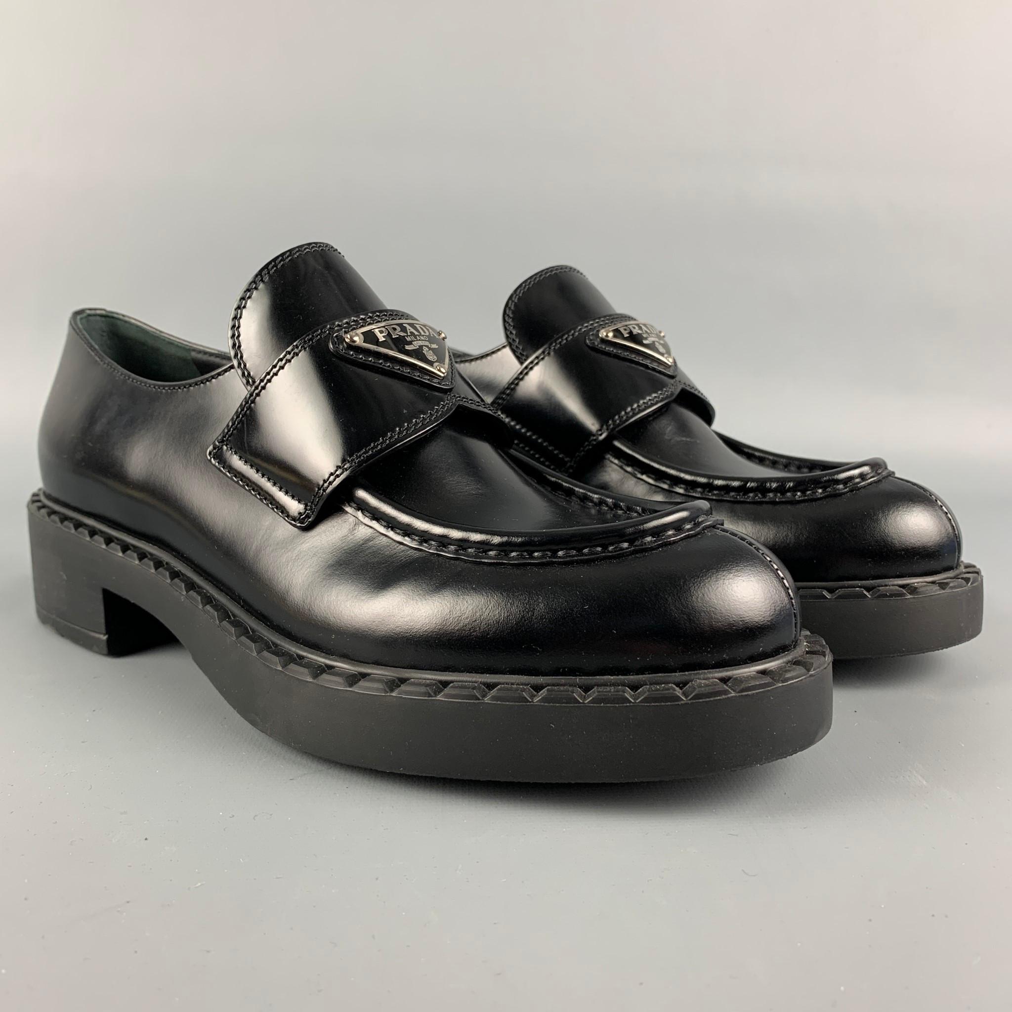 PRADA Loafers aus schwarzem Leder mit runder Mokassin-Zehe:: Schlupf:: Dreieckslogo:: Gummisohle und klobigem Absatz. Hergestellt in Italien. 

Brandneu. 
Markiert: 37.5
Ursprünglicher Verkaufspreis: $975.00

Maße: 

Absatz: 2 in. 
Plattform: 0.5 in.