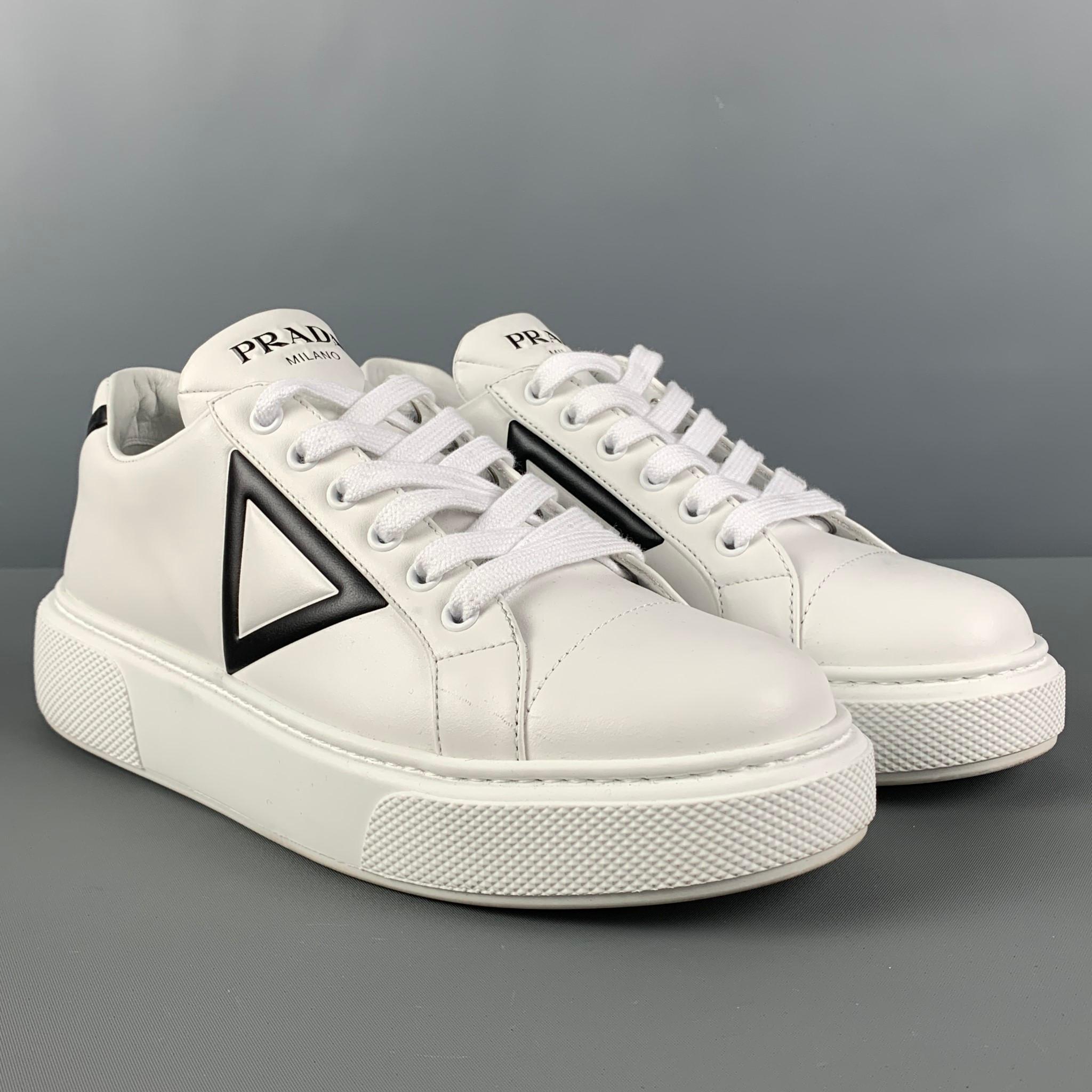 PRADA sneakers comes in a white leather with a black triangle design featuring a low-top style, chunky sole, and a lace up closure. Made in Italy. 

Excellent Pre-Owned Condition.
Marked: 633 37.5

Outsole: 10.75 in. x 4 in.