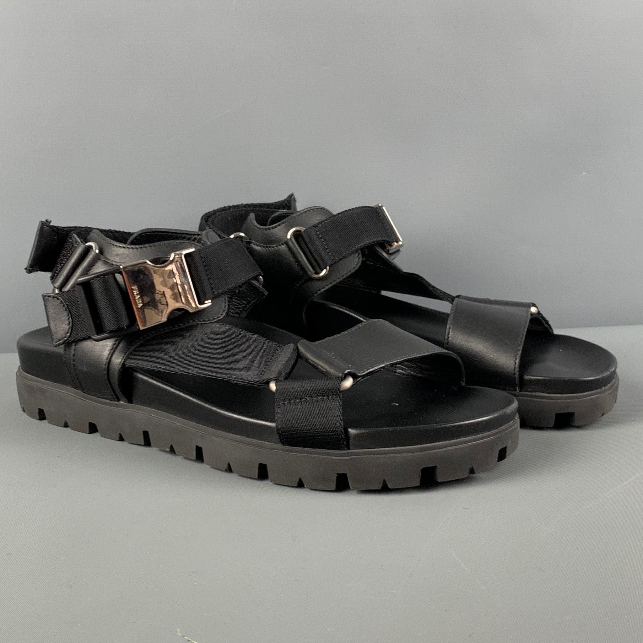 Les sandales PRADA sont en cuir noir et présentent un bout ouvert, des boucles argentées et une fermeture à boucle et crochet à l'arrière. Fabriquées en Italie.
Excellent
Etat d'occasion. 

Marqué :   2X3055 7Semelle : 11 pouces  x 4 pouces 
  
  
