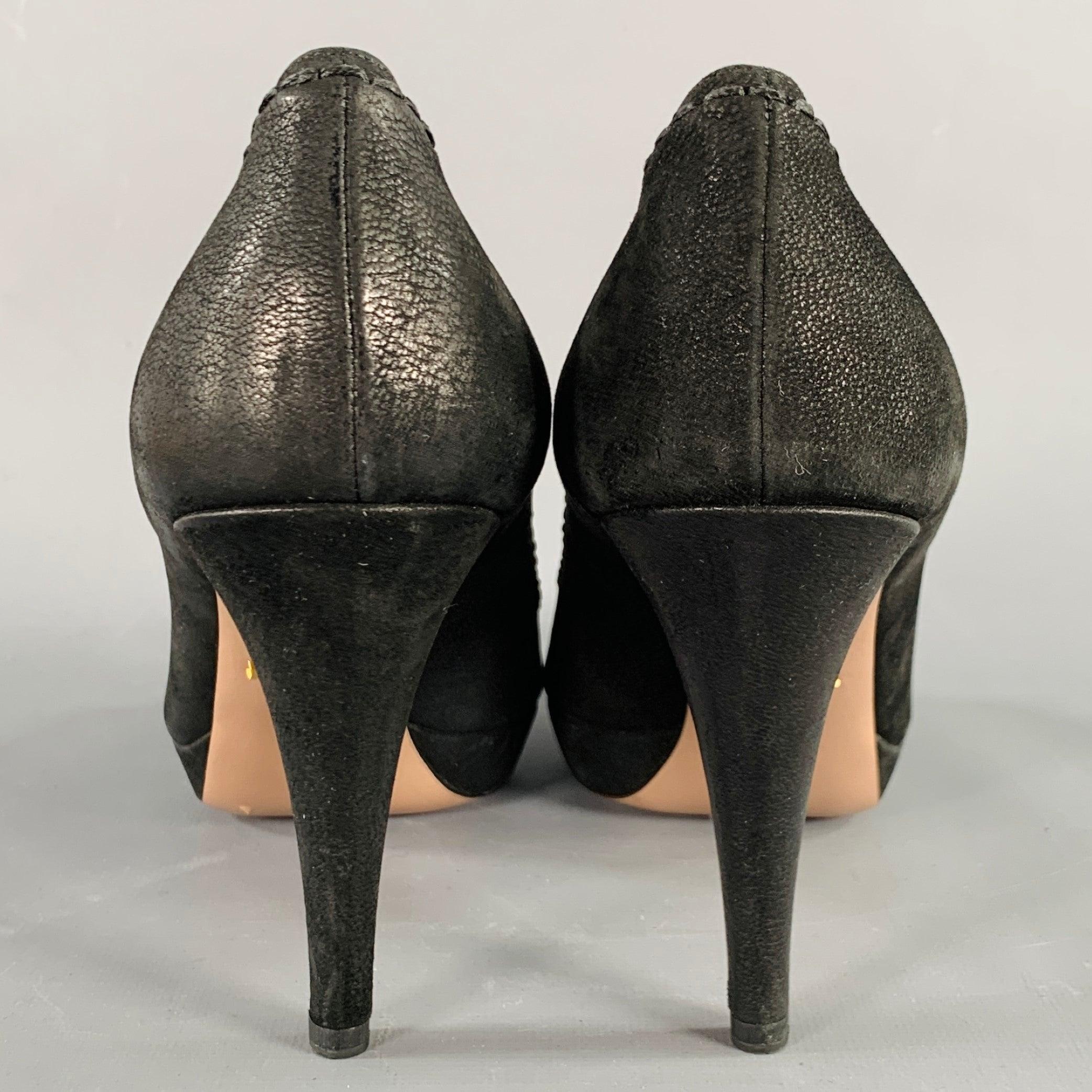 PRADA pumps
in a black leather featuring a platform style, peep toe, and stitching details. Made in Italy.Very Good Pre-Owned Condition. Signs of wear on soles. 

Marked:   IT 38 

Measurements: 
  Heel: 4 inches Platform: 0.5 inches 
  
  
 
Sui