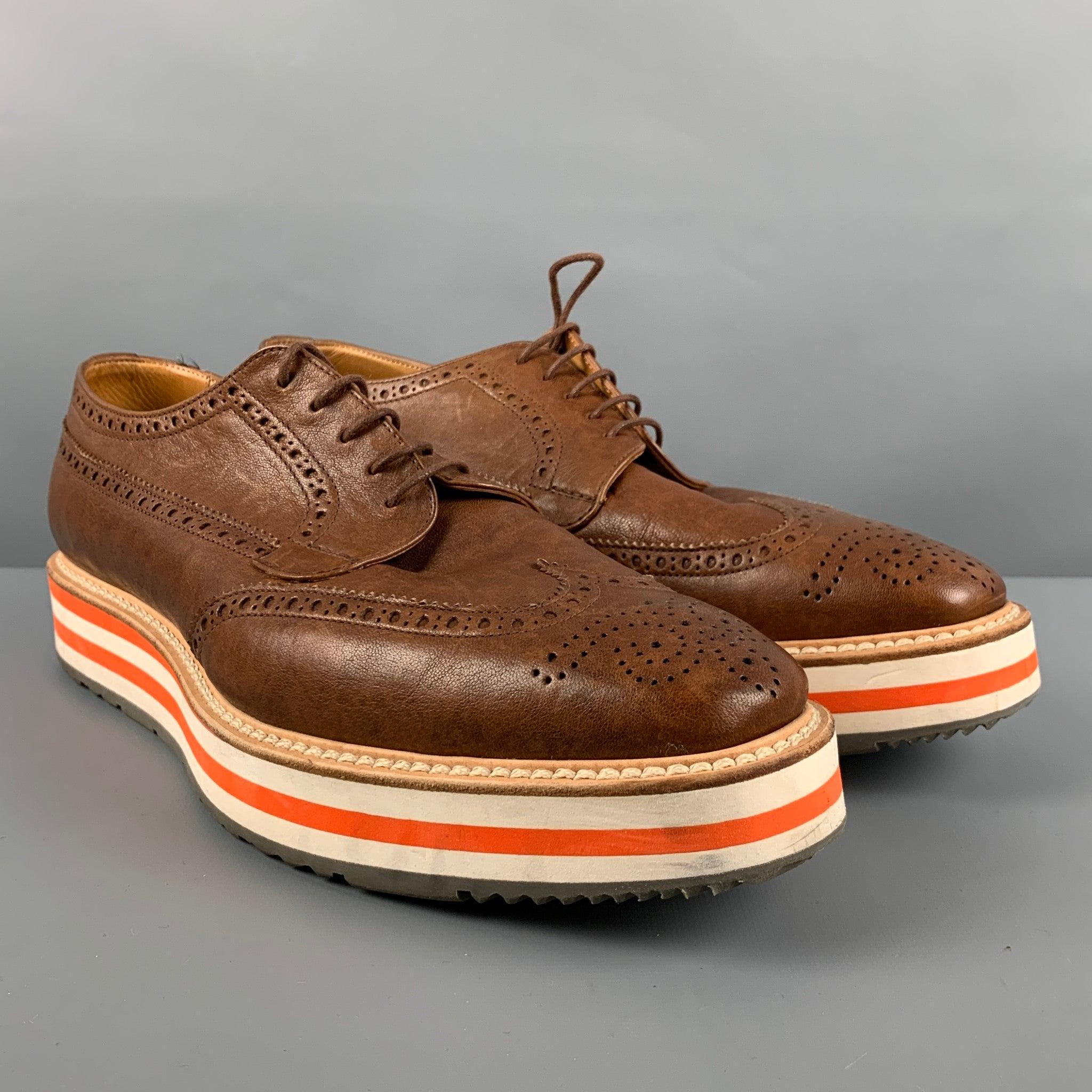 PRADA shoes comes in a brown perforated leather featuring a wingtip style, rubber platform sole, and a lace up closure. Comes with Box and Dust Bag.Made in Italy. Very Good Pre-Owned Condition. Minor signs of wear. 

Marked:   2EG 015 81/2Outsole: