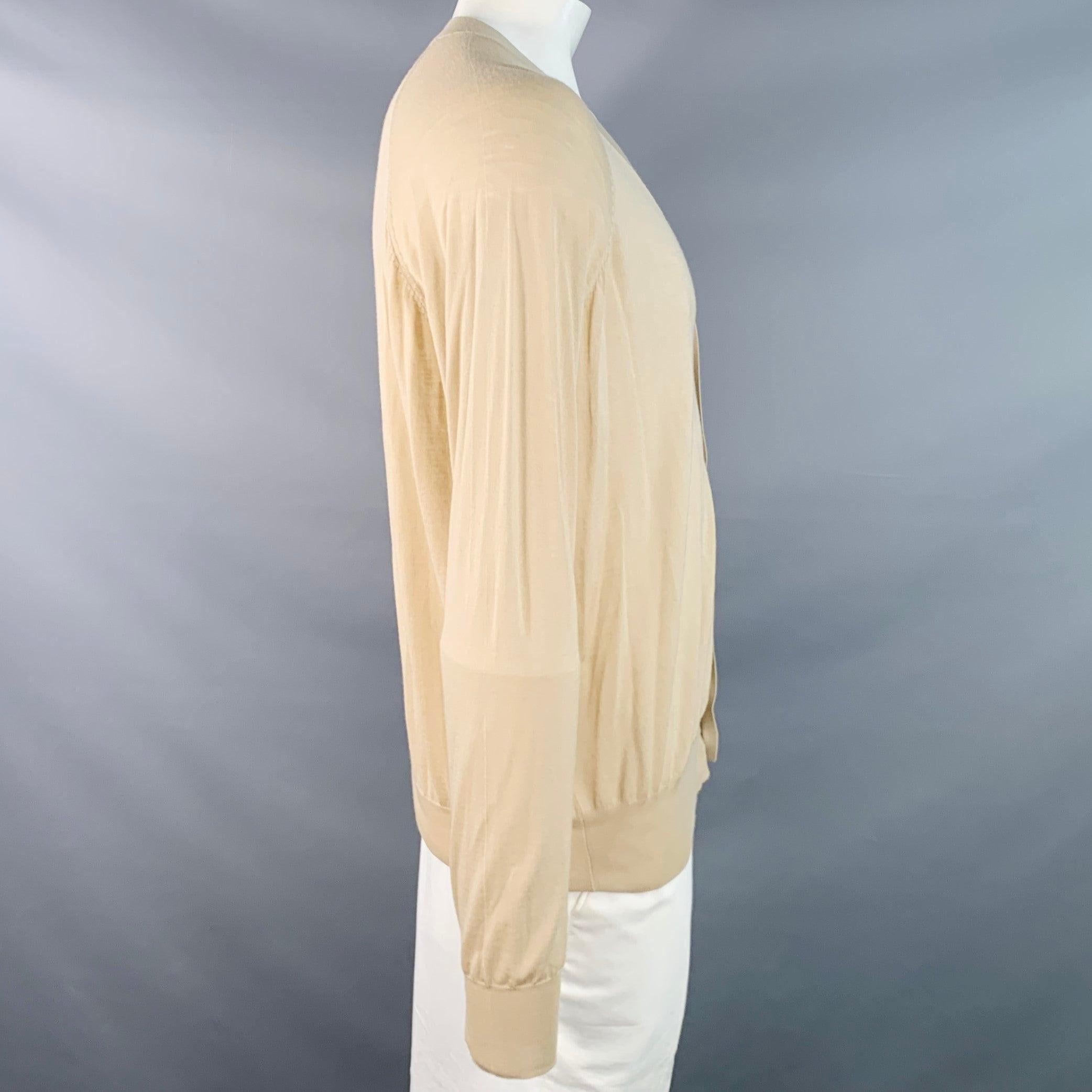 Cardigan PRADA
en maille de laine vierge beige transparente, avec manches longues raglan et fermeture boutonnée à l'encolure en V. Fabriqué en Italie. Bon état d'usage. Petites lacunes. 

Marqué :   IT 52 

Mesures : 
 
Épaule : 16 pouces Poitrine :